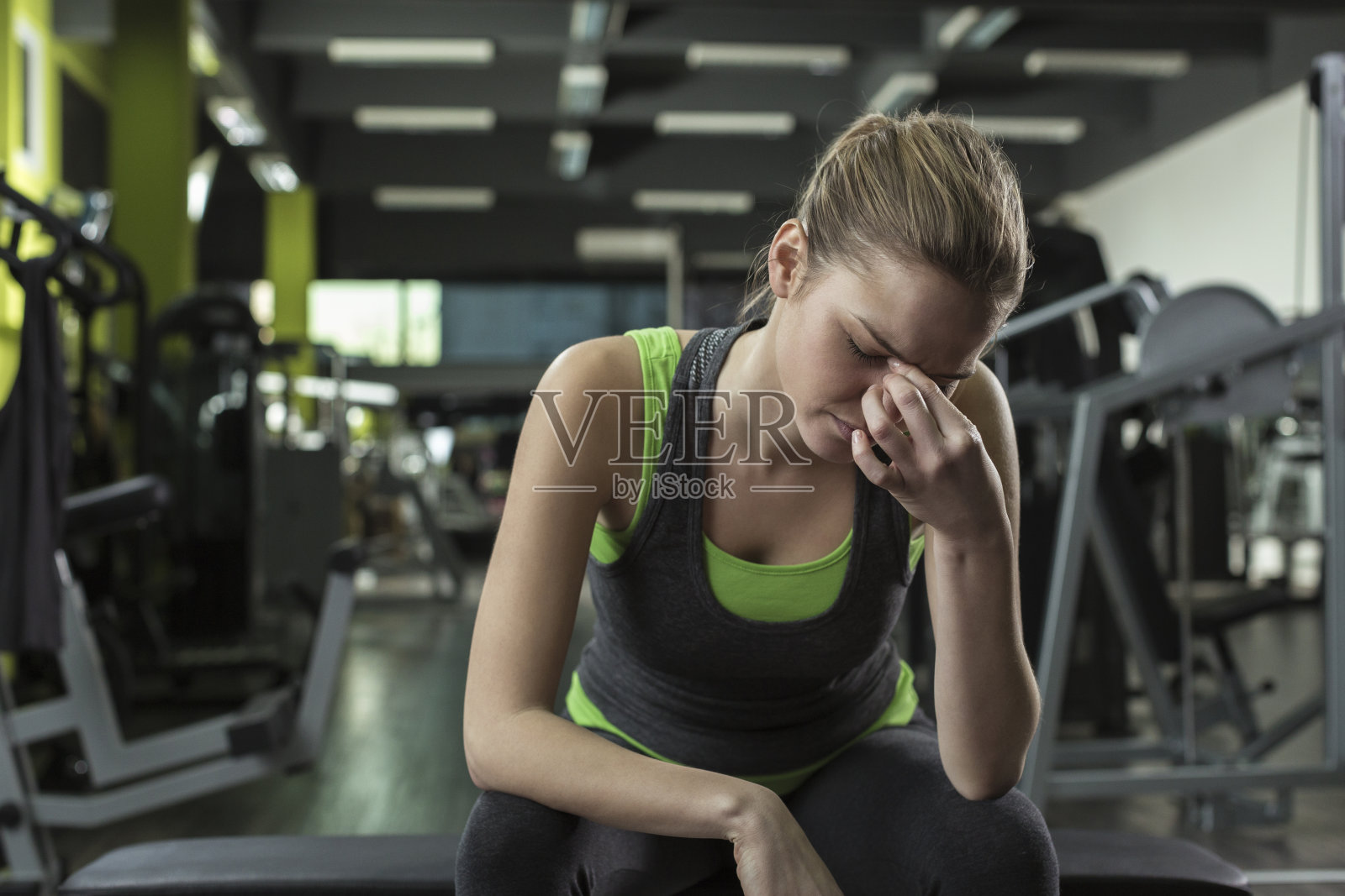 在健身俱乐部锻炼后头痛的妇女照片摄影图片