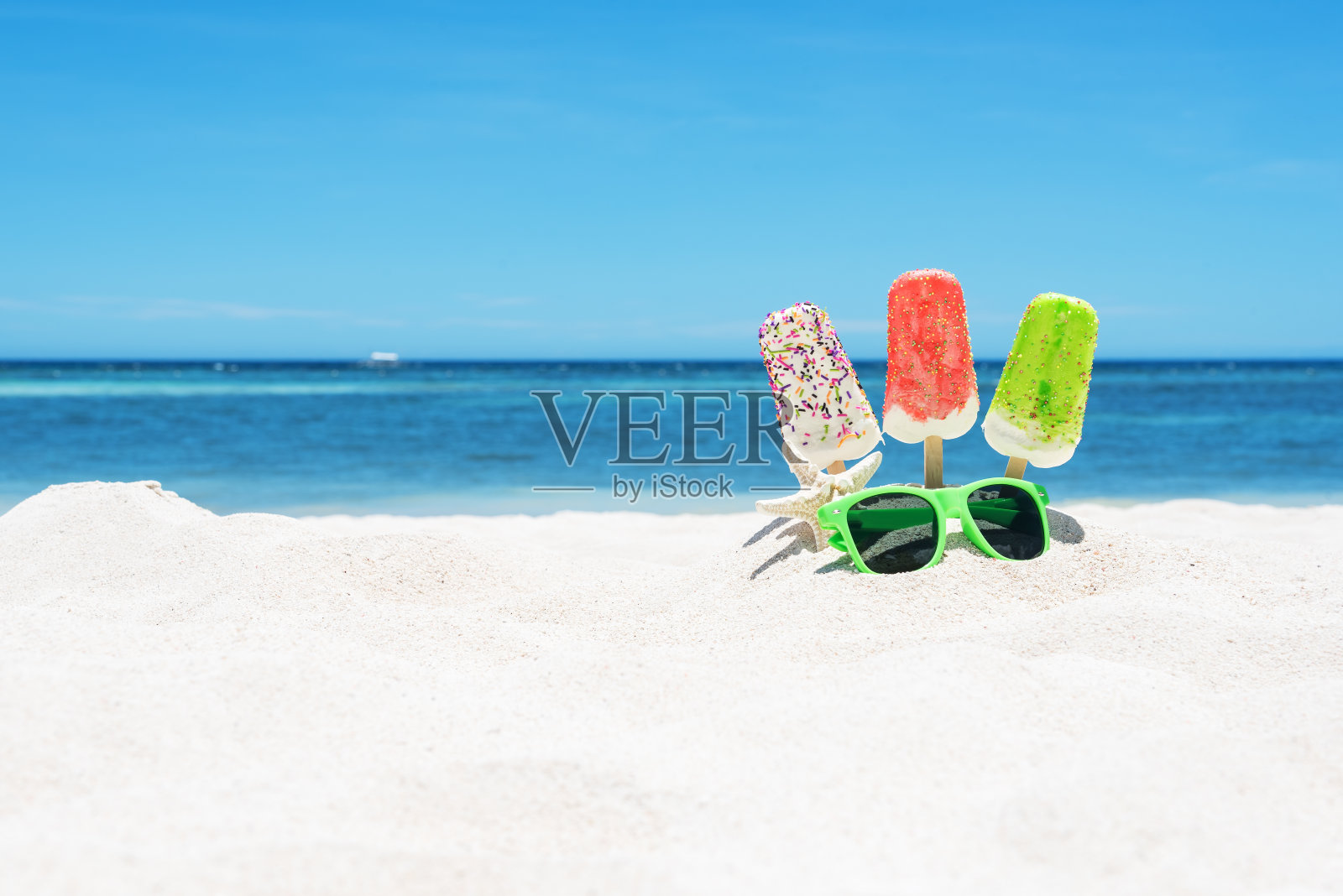 白色的沙滩上有冰淇淋、冰棒和太阳镜照片摄影图片