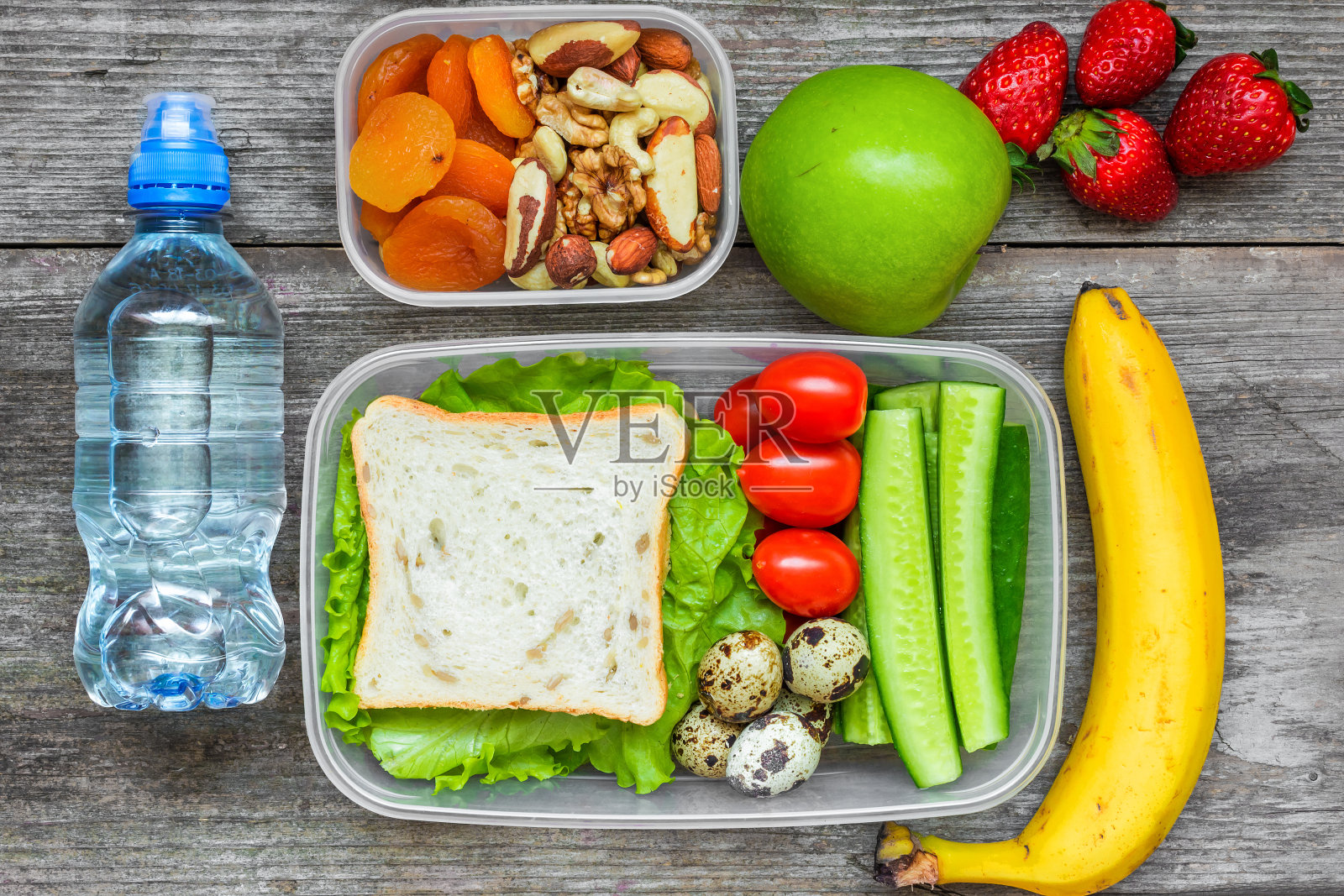 学校午餐盒有三明治，鸡蛋和新鲜蔬菜，一瓶水，坚果和水果照片摄影图片
