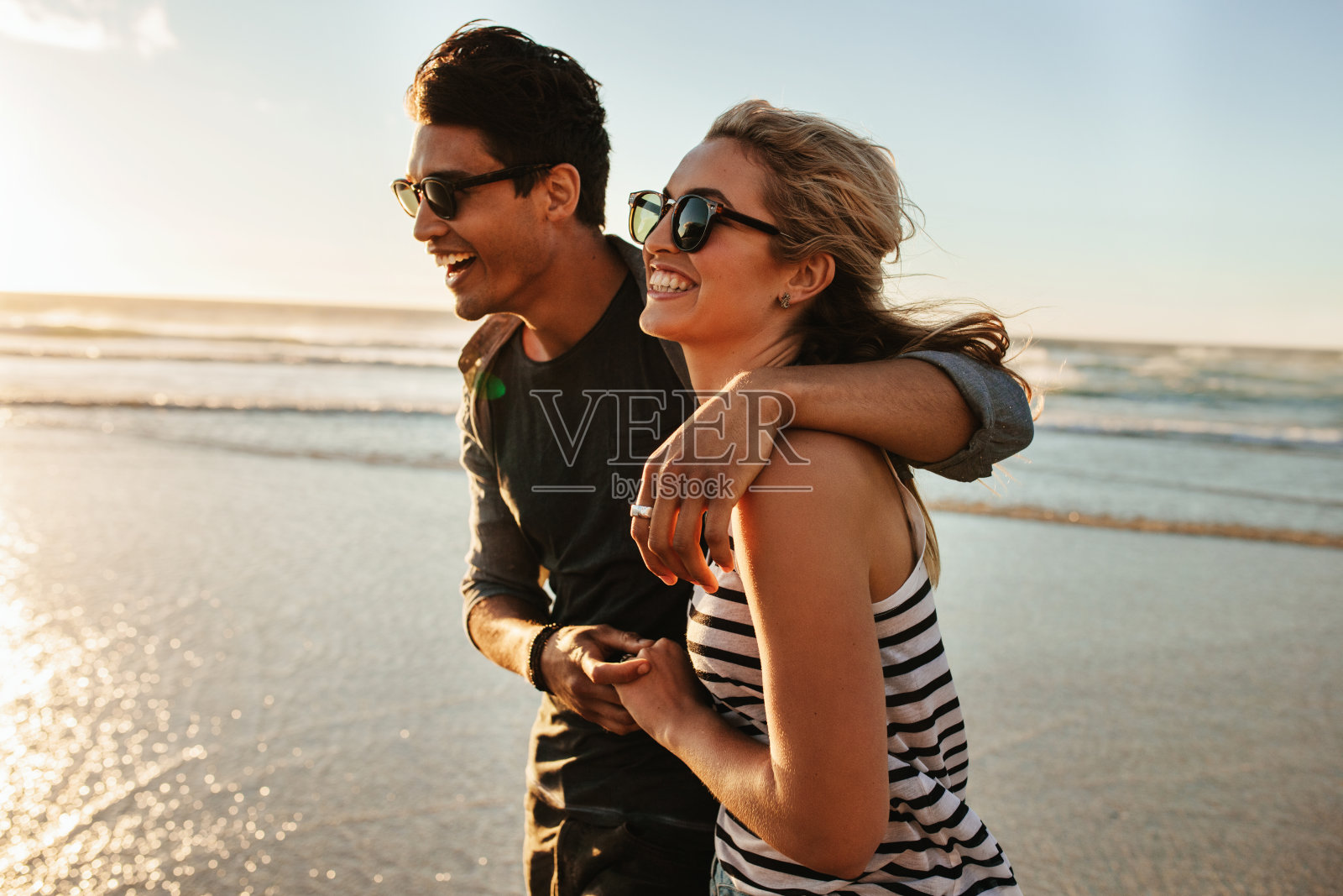 微笑的年轻夫妇在海滩上散步照片摄影图片