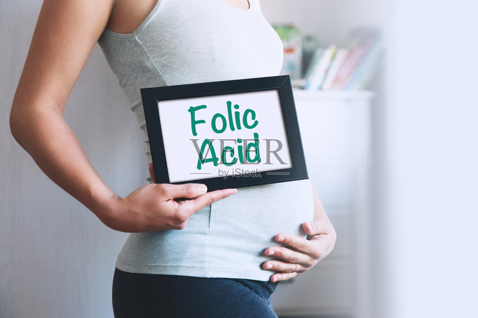 一名孕妇手持白板，上面写着关于叶酸的文字信息。照片摄影图片