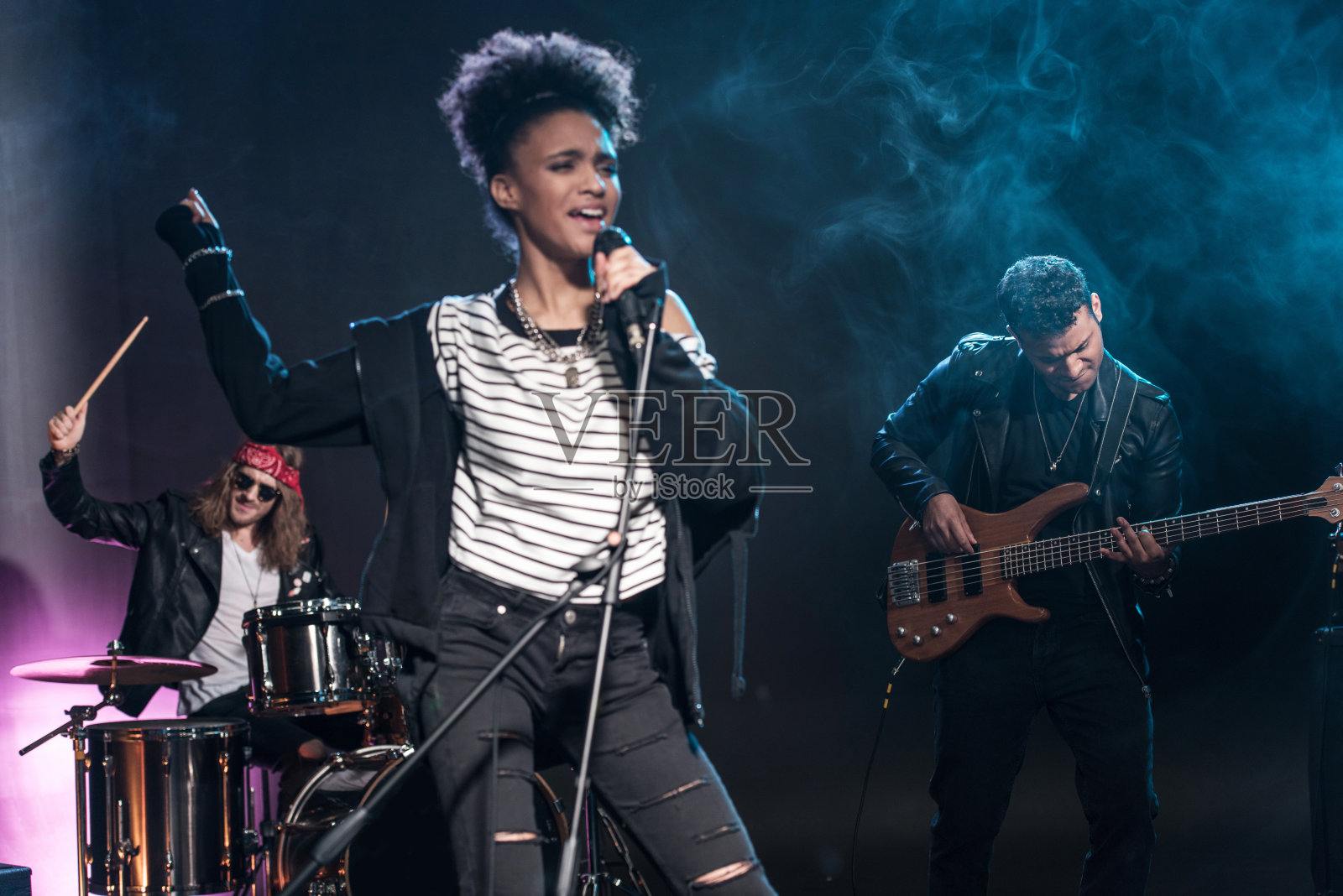 女歌手拿着麦克风和摇滚乐队在舞台上表演硬摇滚音乐照片摄影图片