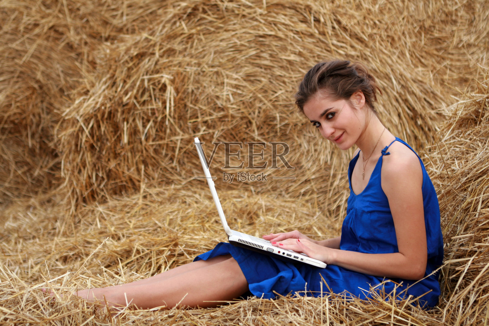 年轻漂亮的女人微笑着在笔记本电脑上打字照片摄影图片
