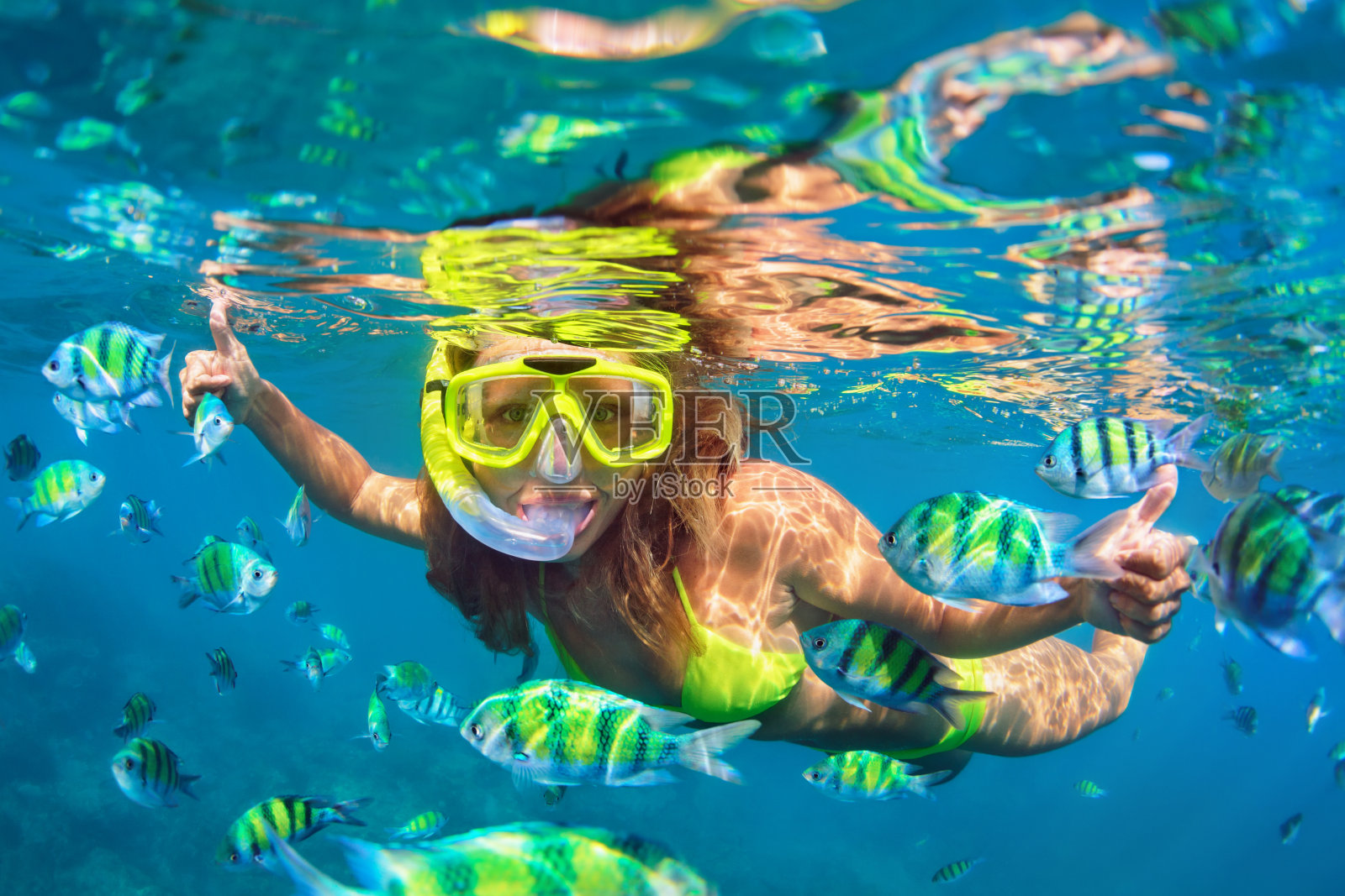 戴着浮潜面罩的女孩和珊瑚礁里的鱼一起潜水照片摄影图片