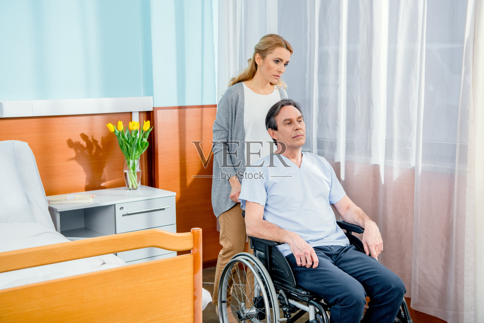 轮椅男人和妻子在医院的房间附近照片摄影图片