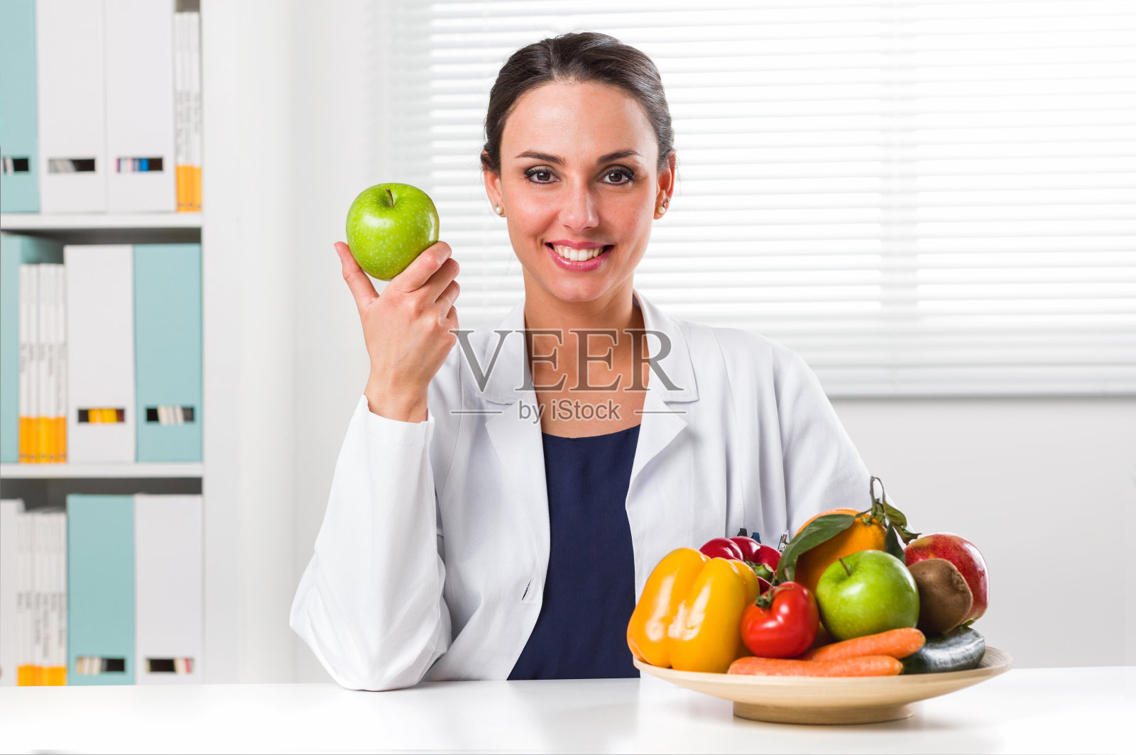 女性营养学家拿着一个青苹果照片摄影图片