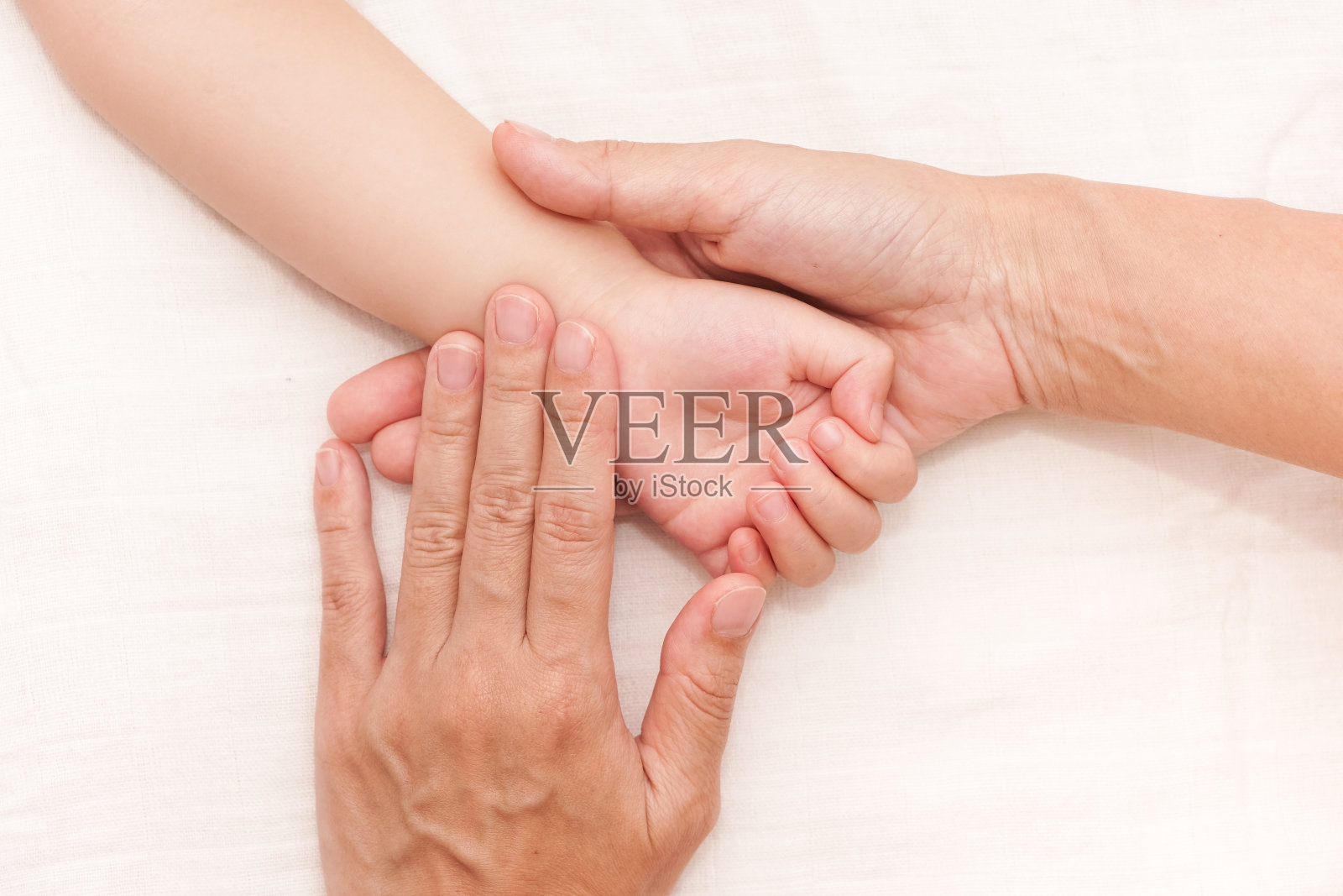 妈妈的两只手牵着宝宝的一只手。照片摄影图片