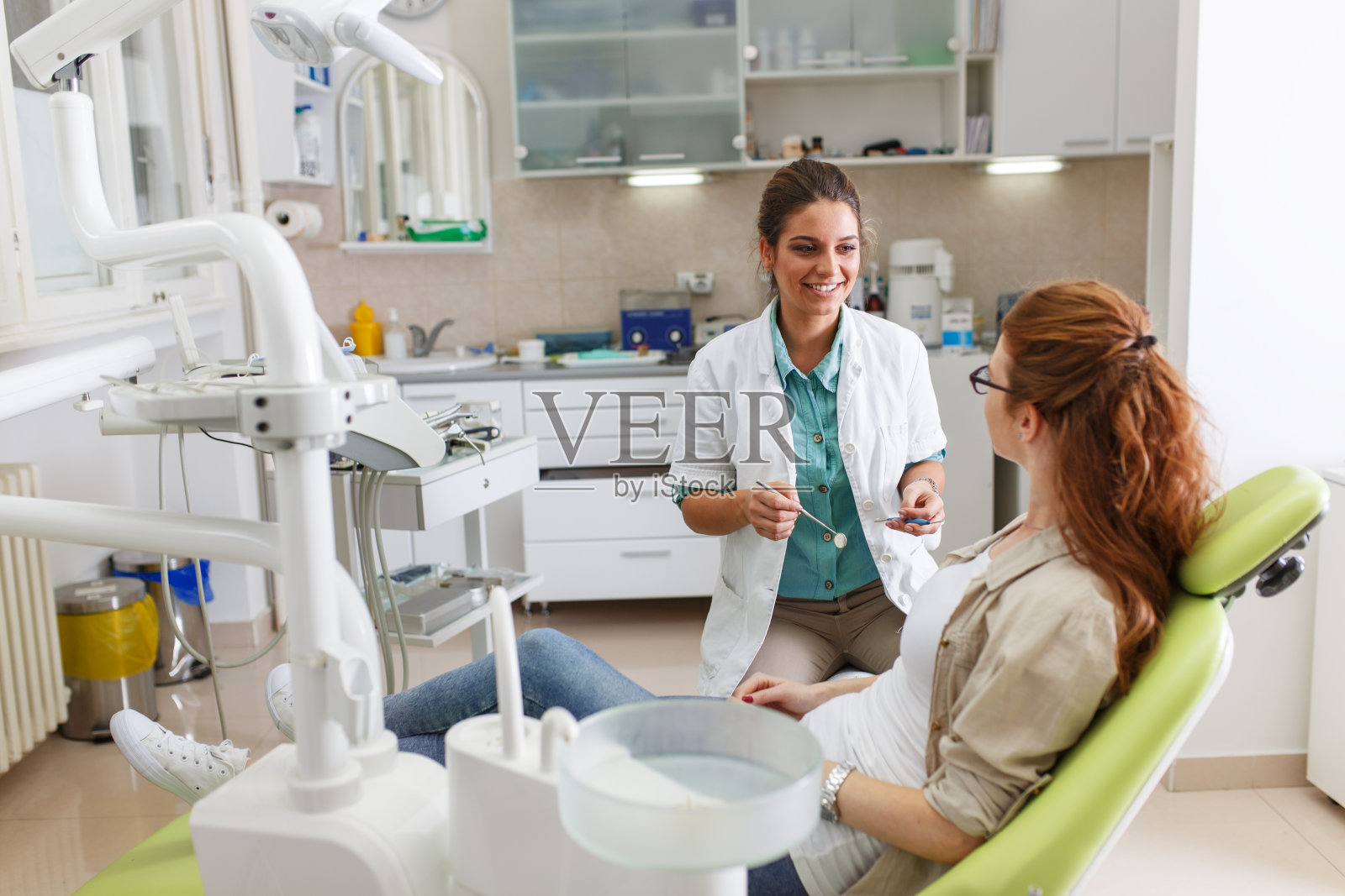 女牙医在牙科诊所与女病人交谈照片摄影图片