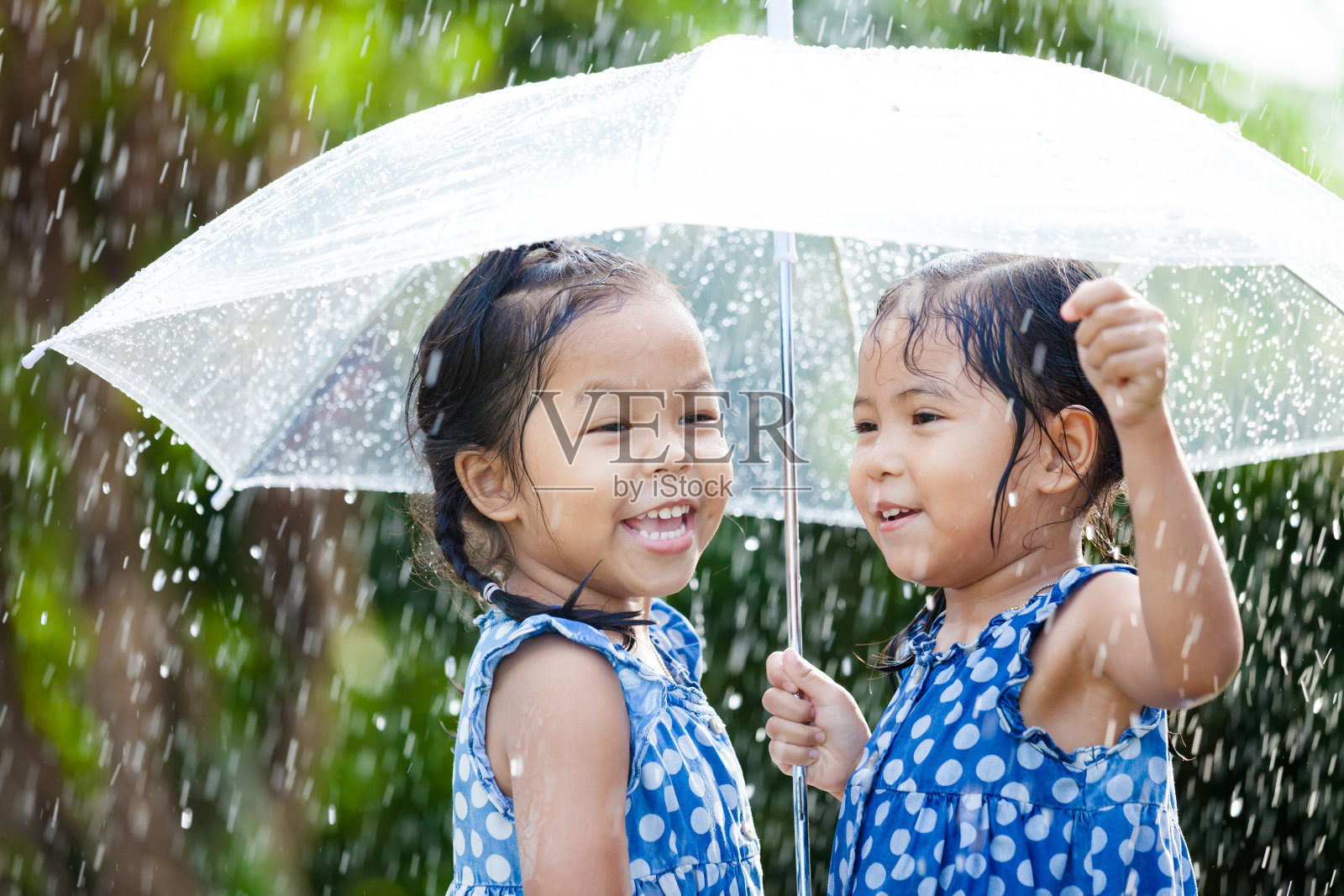 两个快乐的亚洲小女孩带着伞一起玩雨照片摄影图片