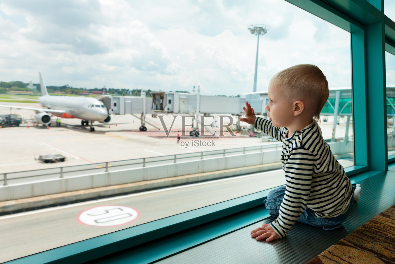 在机场大厅里，孩子透过窗户看飞机照片摄影图片