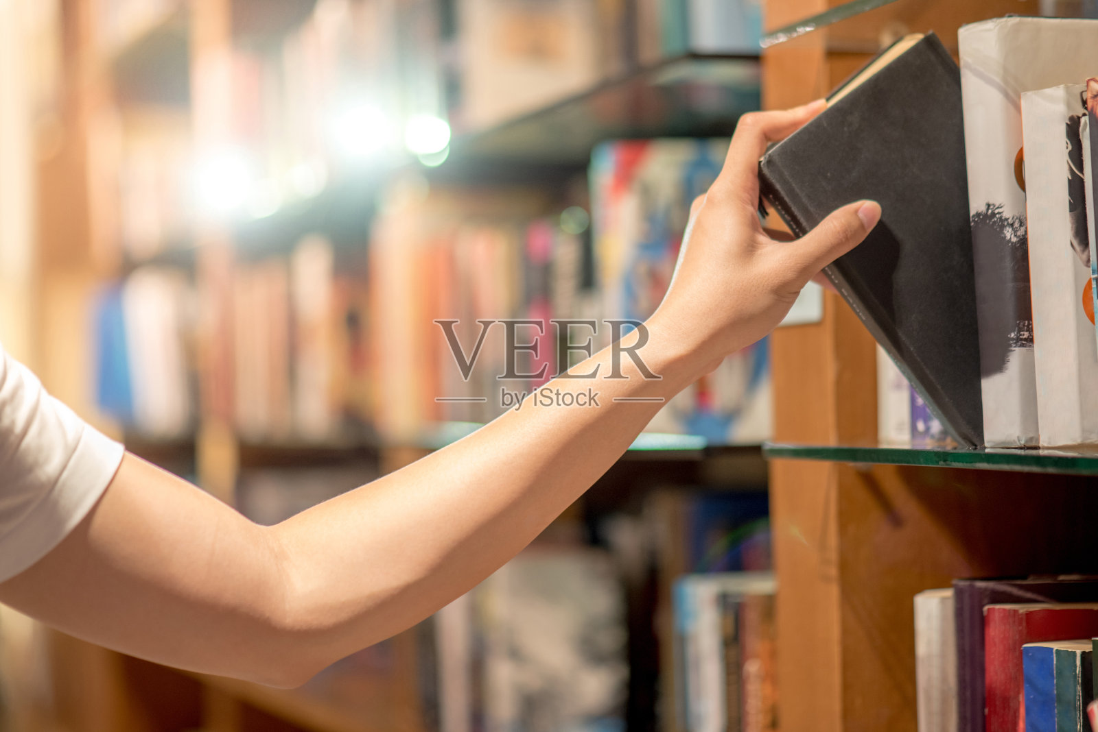 从图书馆的书架上挑书的年轻人的右手照片摄影图片