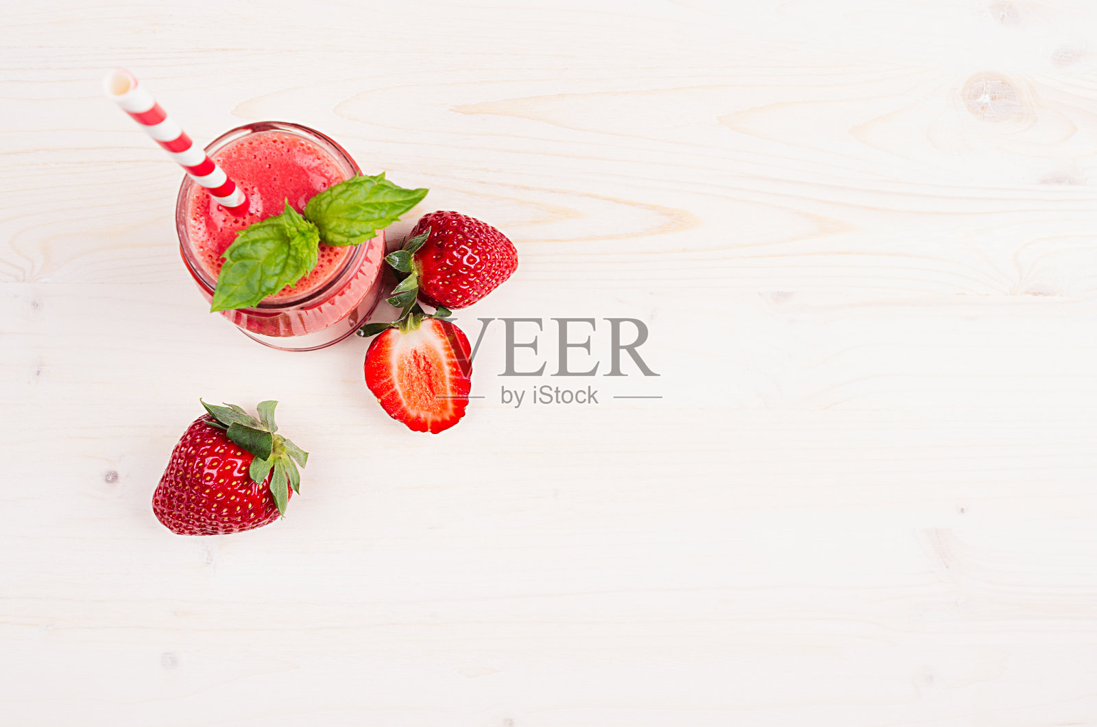 新鲜混合红草莓水果冰沙与吸管，薄荷叶，切熟的浆果，俯视图。白色木板背景，复制空间。照片摄影图片