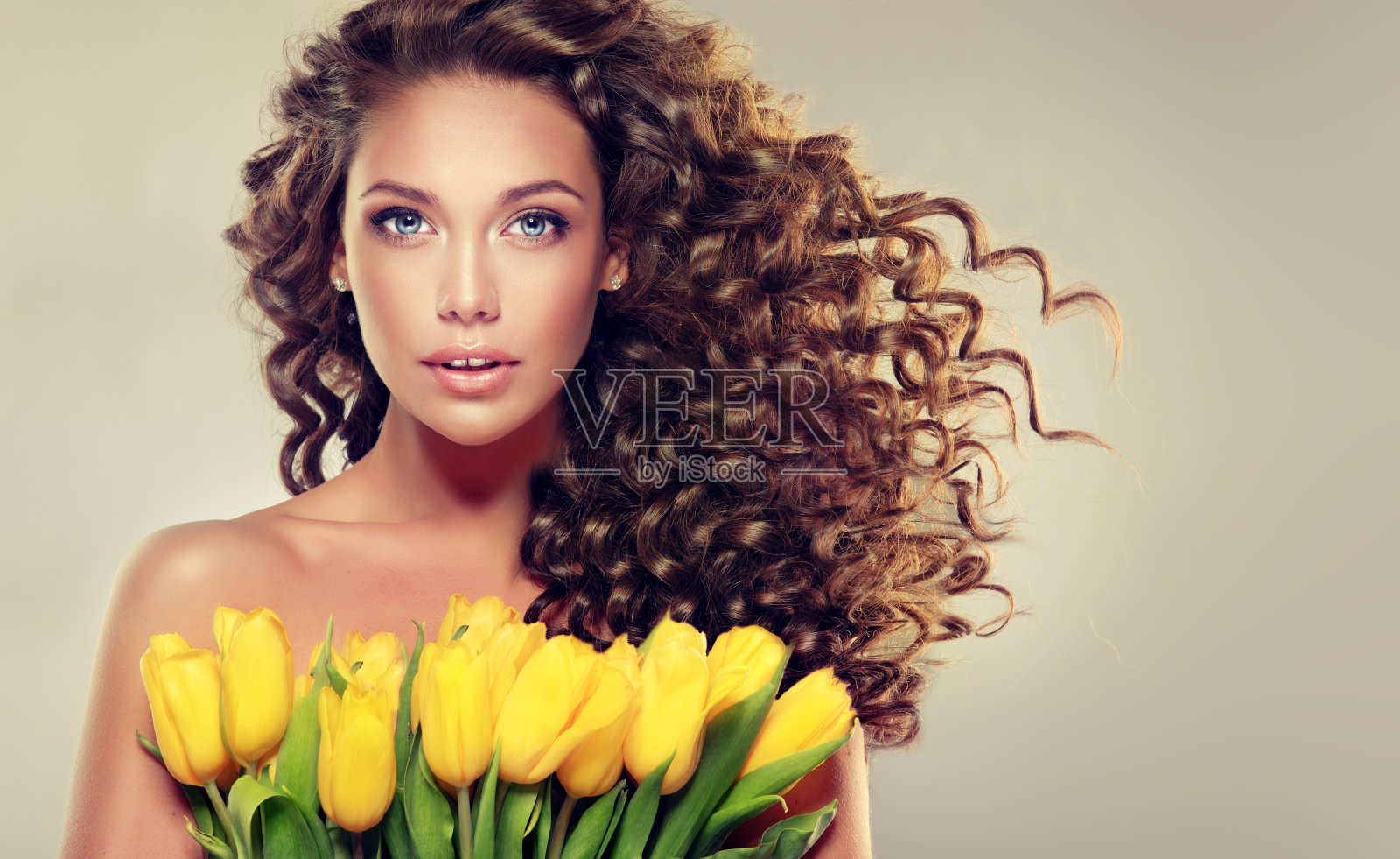 年轻的黑发女人手里拿着黄色的郁金香。照片摄影图片