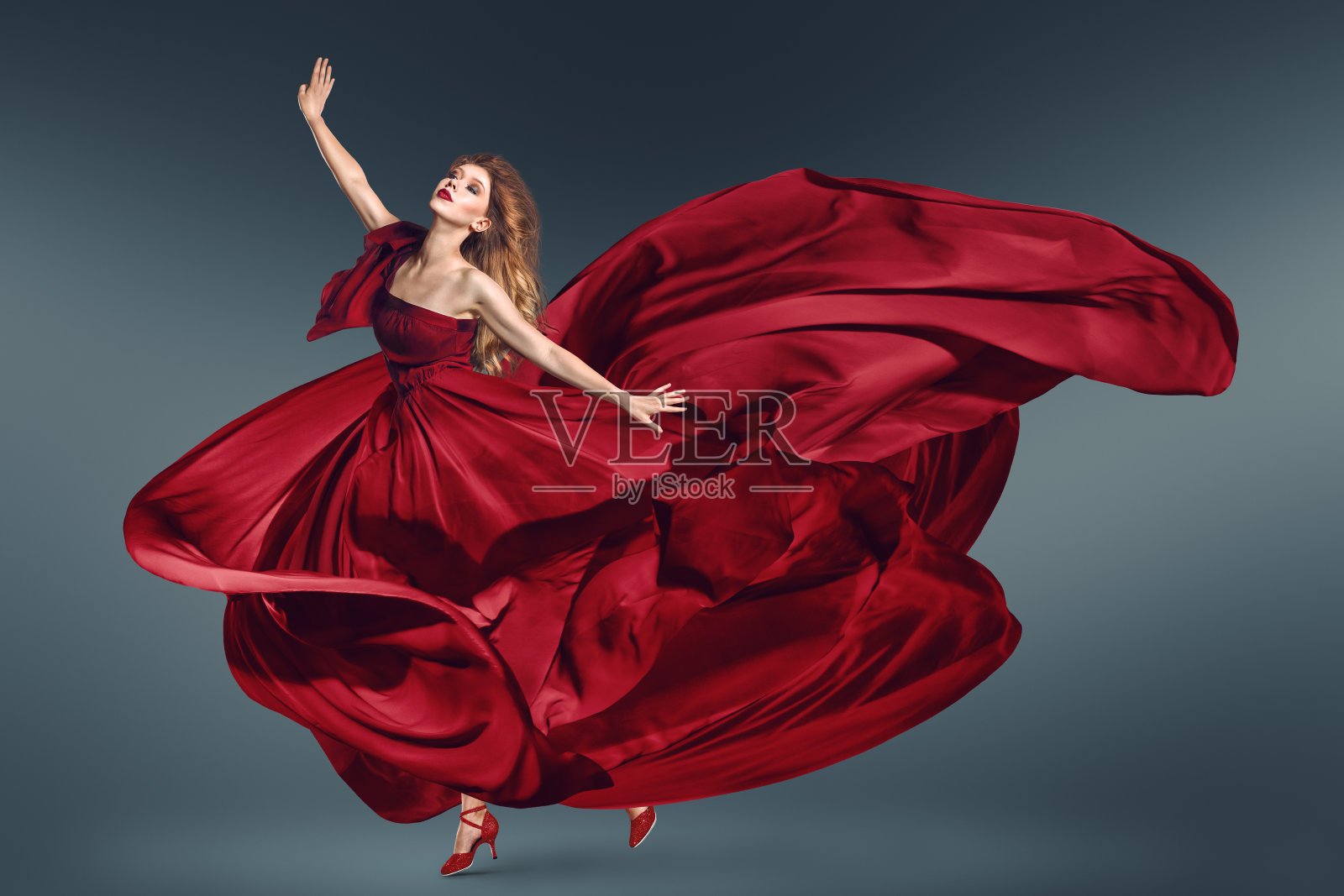 穿着飘动的红色连衣裙跳舞的时尚女子照片摄影图片
