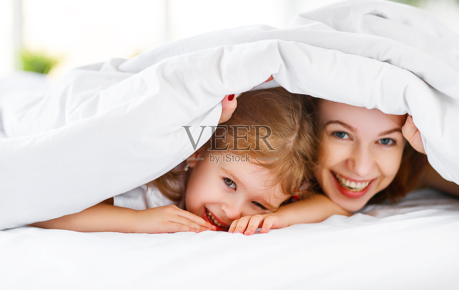 幸福的家庭妈妈和孩子女儿在床上笑照片摄影图片
