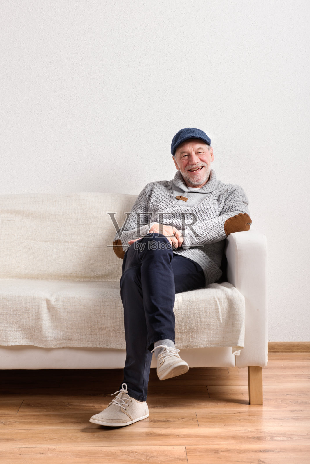 老男人穿着灰色毛衣坐在沙发上，拍摄影棚。照片摄影图片