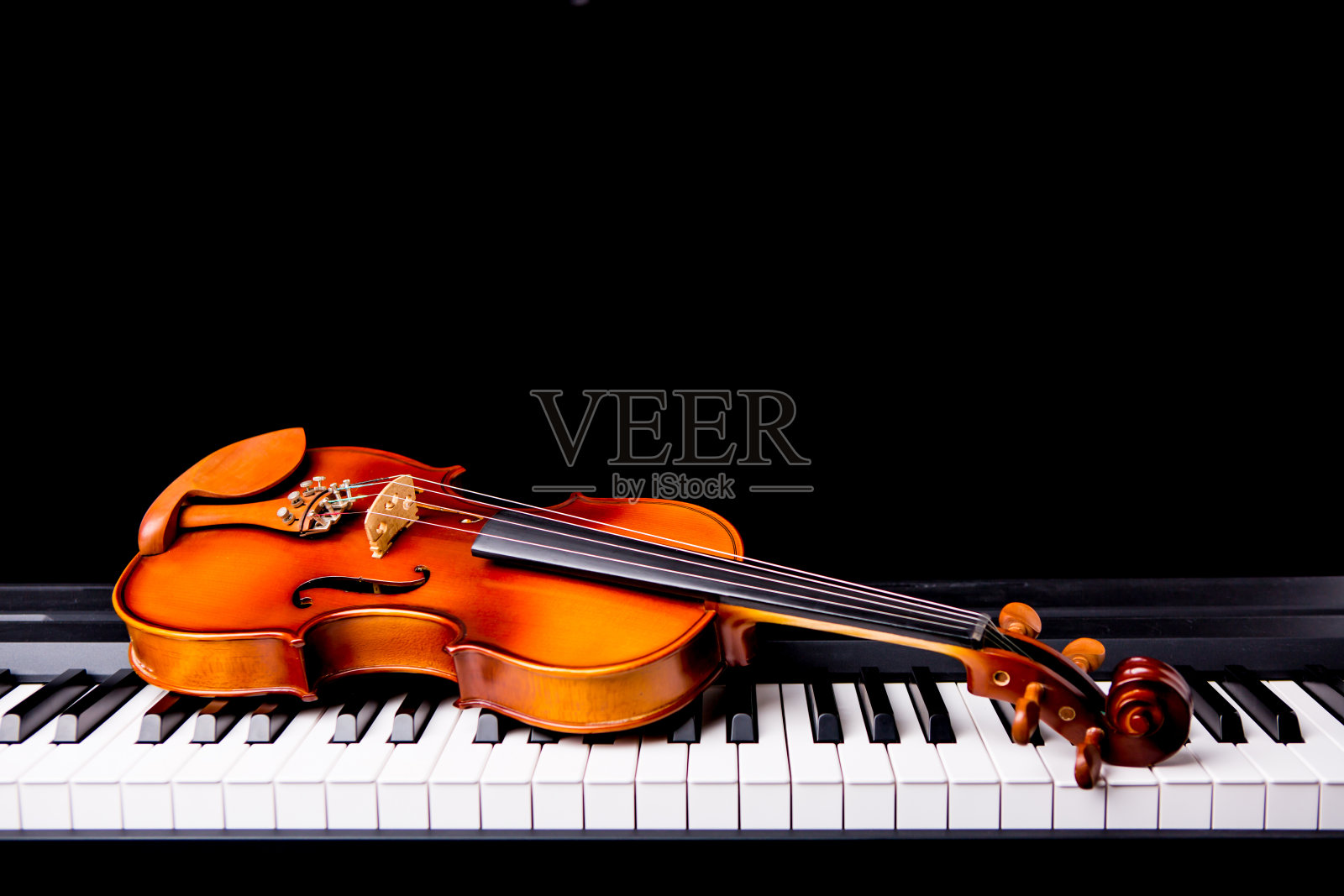 黑色背景是钢琴上的小提琴照片摄影图片