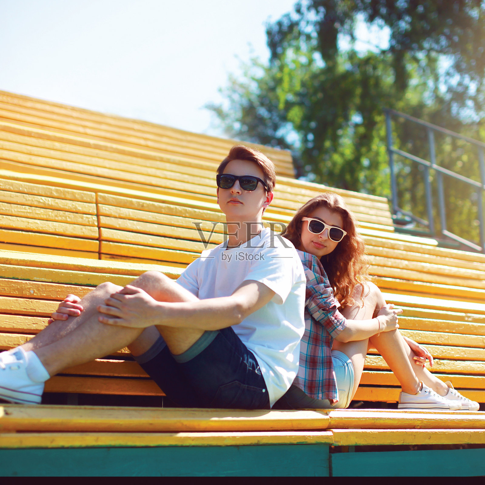 一对戴着太阳镜的时尚潮人夫妇坐在城市的长椅上照片摄影图片