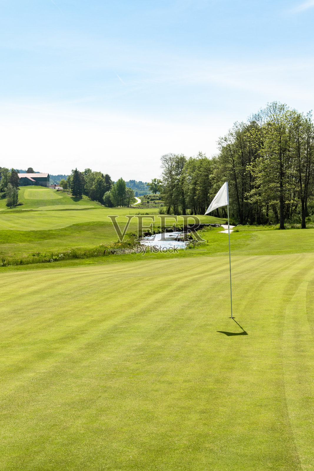 高尔夫球场。洞口挂着一面白旗，天气晴朗照片摄影图片