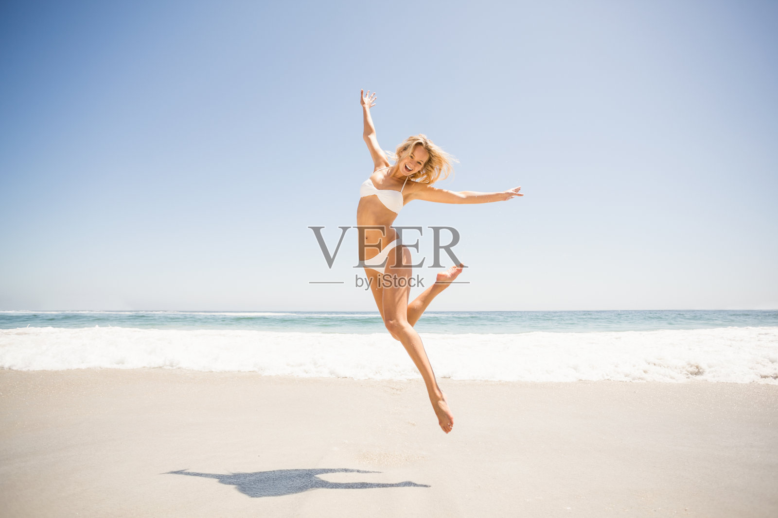 在海滩上跳的女人照片摄影图片