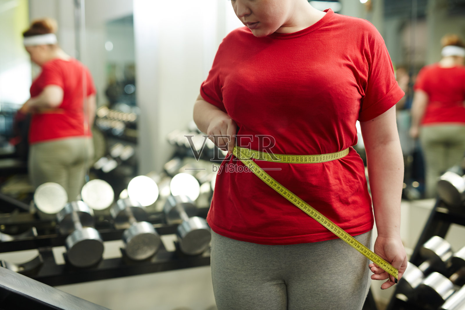 超重妇女在健身房测量腰围照片摄影图片