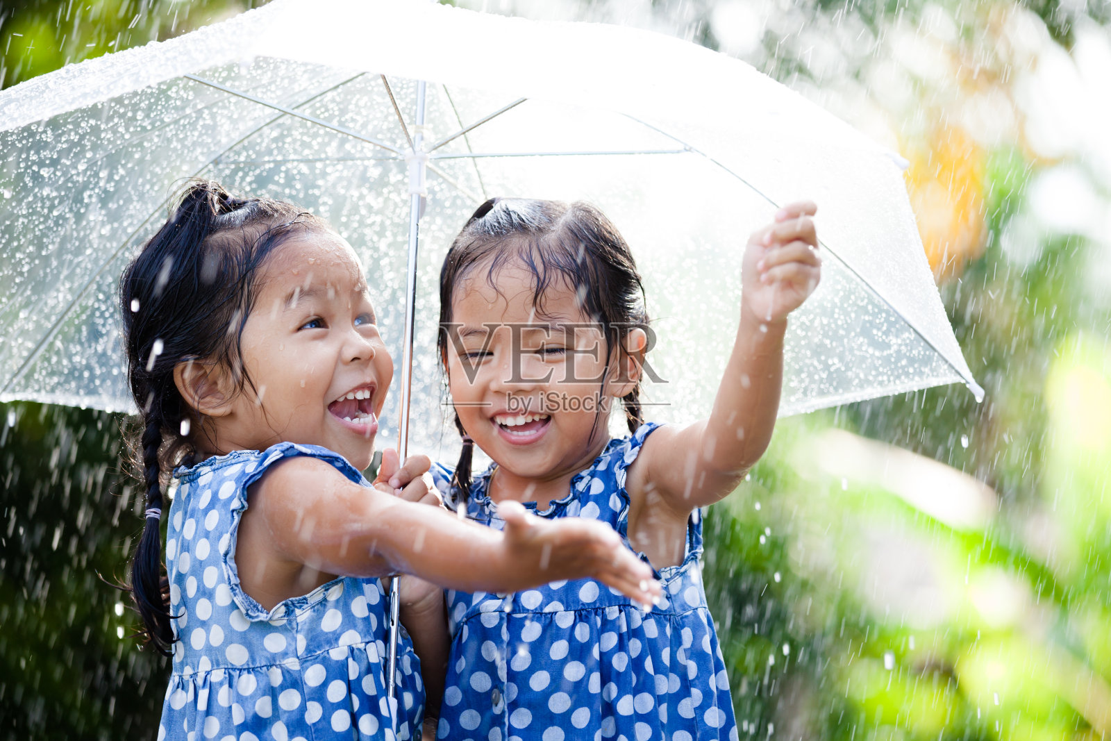两个快乐的亚洲小女孩带着伞一起玩雨照片摄影图片