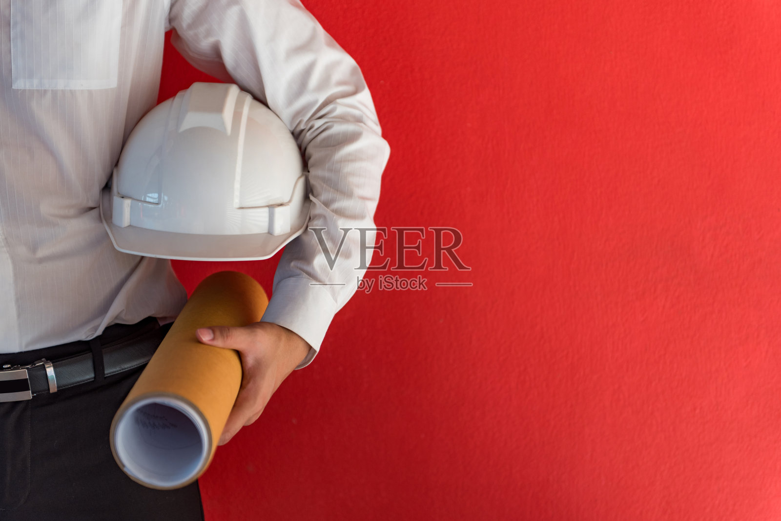 工程师或建筑师手持安全帽，红色背景为建筑图纸照片摄影图片