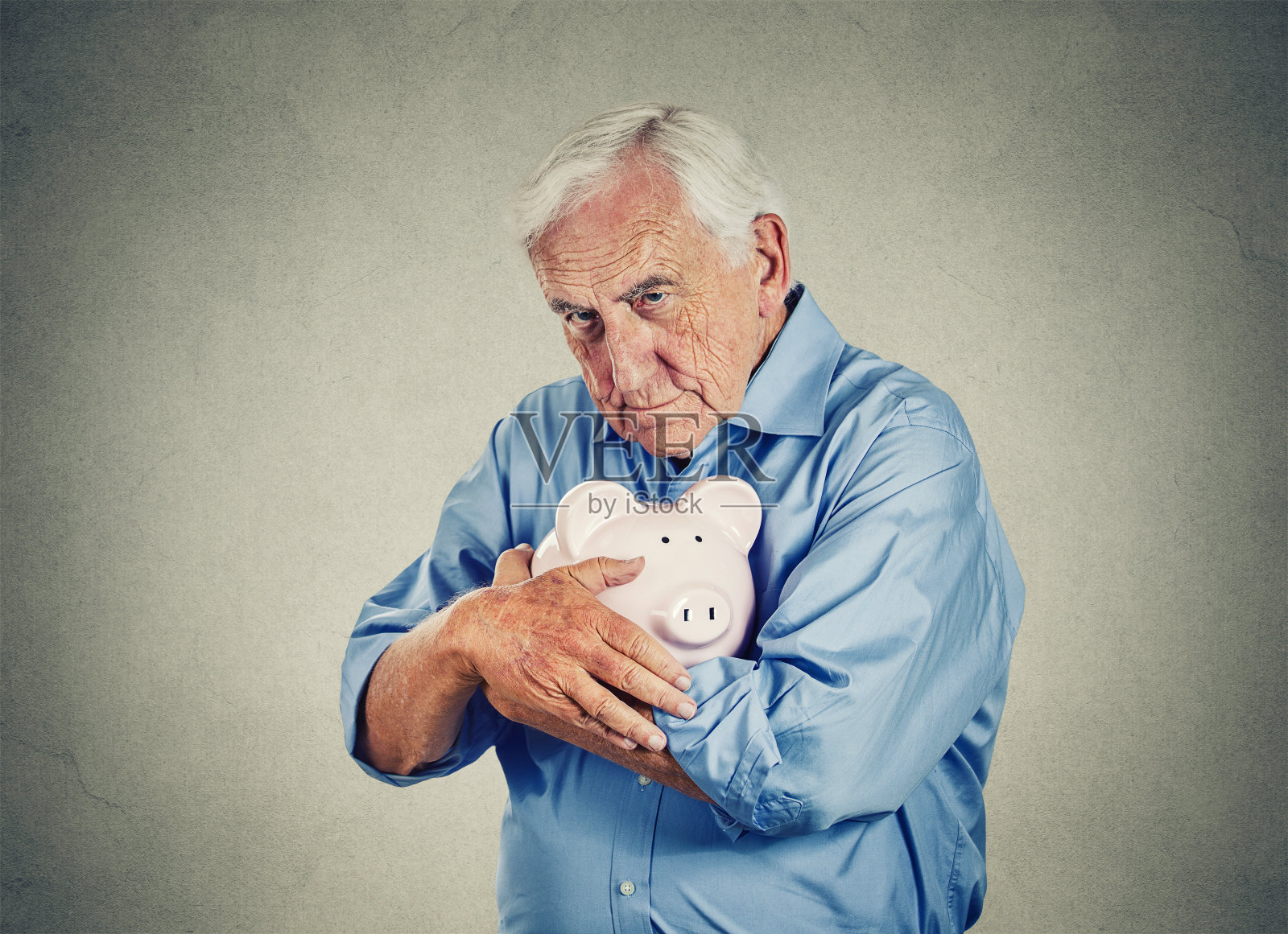 年长男子抱着储蓄罐孤立在灰色的墙壁背景照片摄影图片