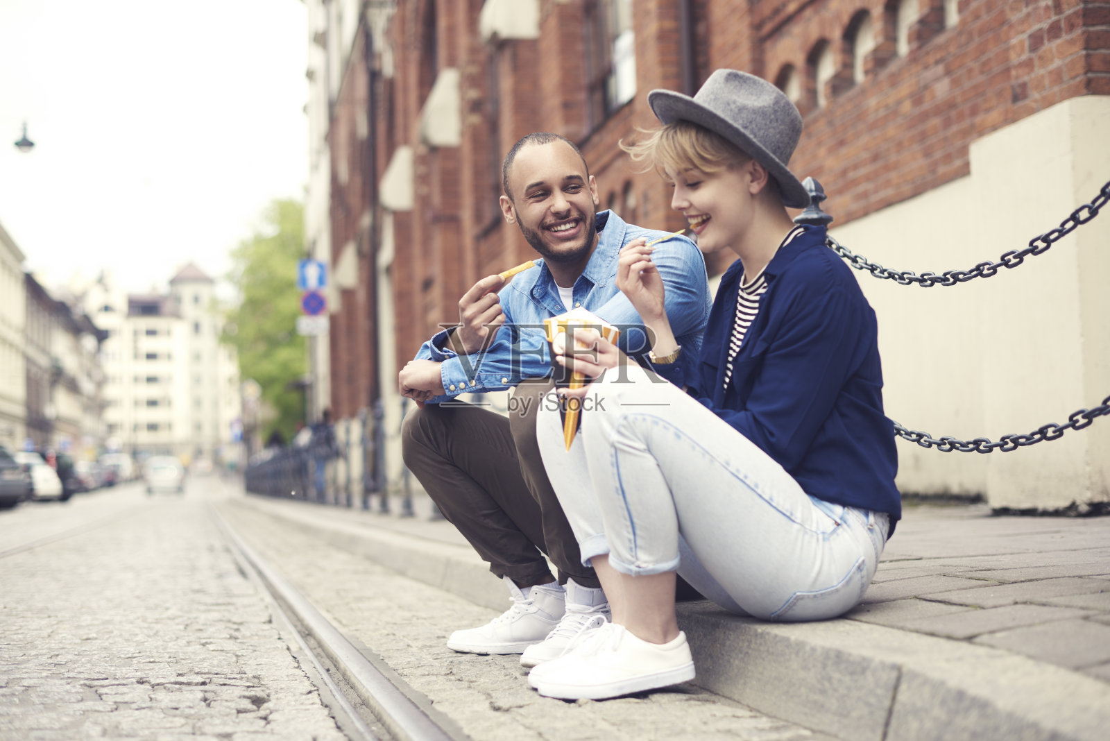 一对夫妇坐在人行道上吃快餐照片摄影图片