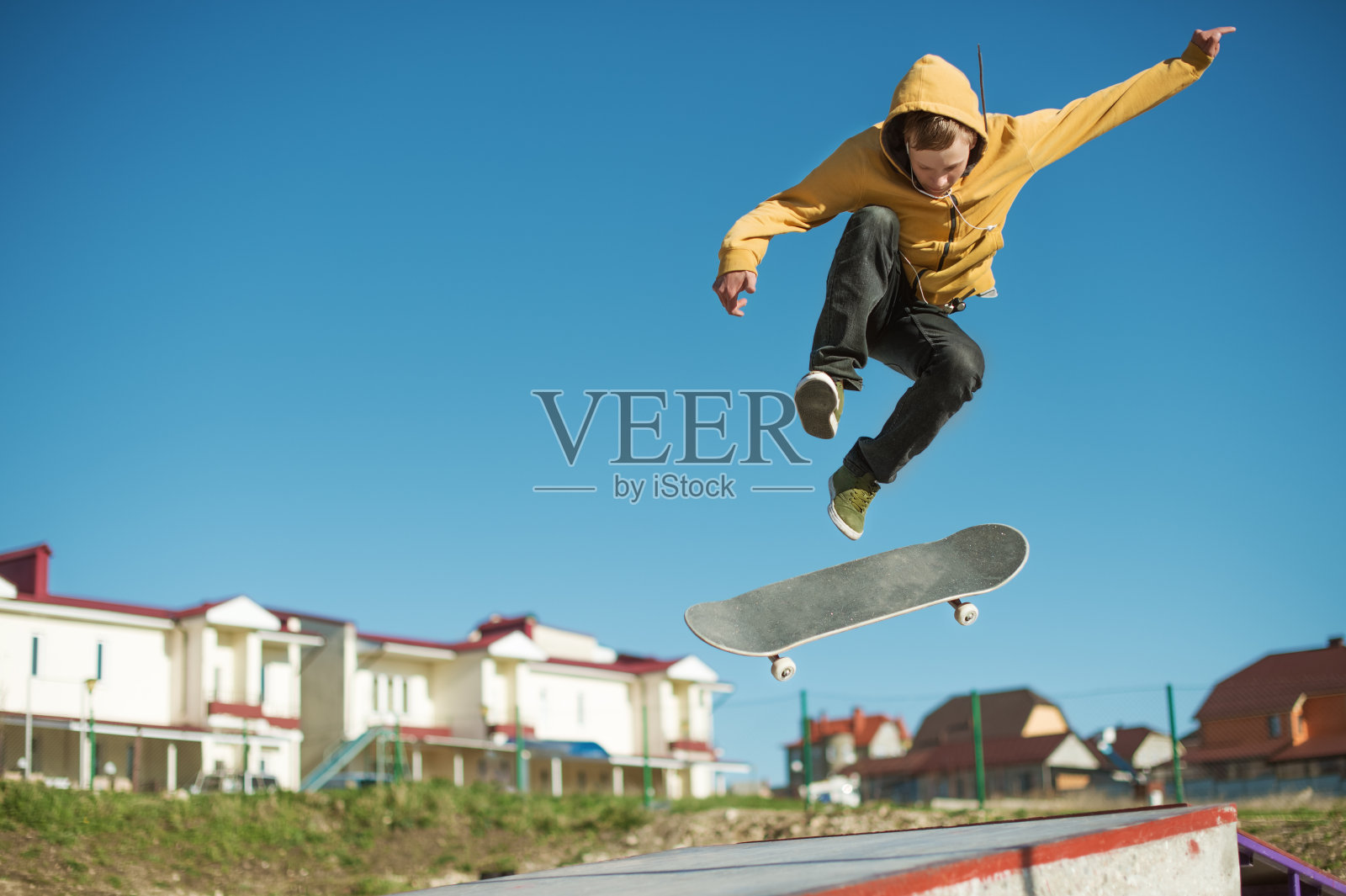 一个十几岁的滑板爱好者在城市郊区的一个滑板公园里玩翻转戏法照片摄影图片