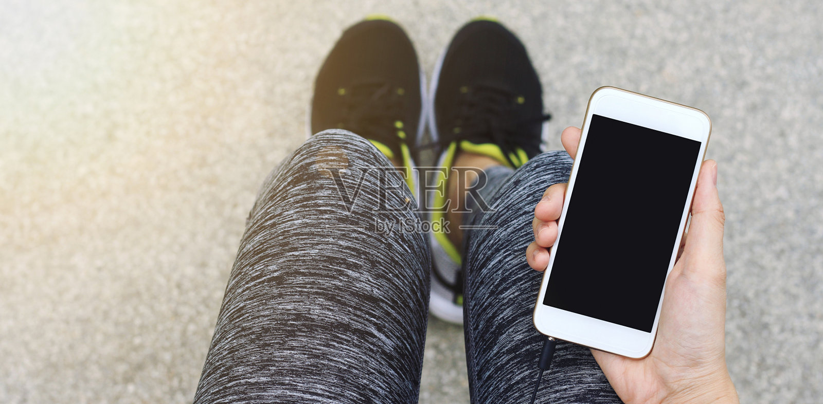慢跑者使用智能手机，女性跑步者在休息时拿着手机。照片摄影图片