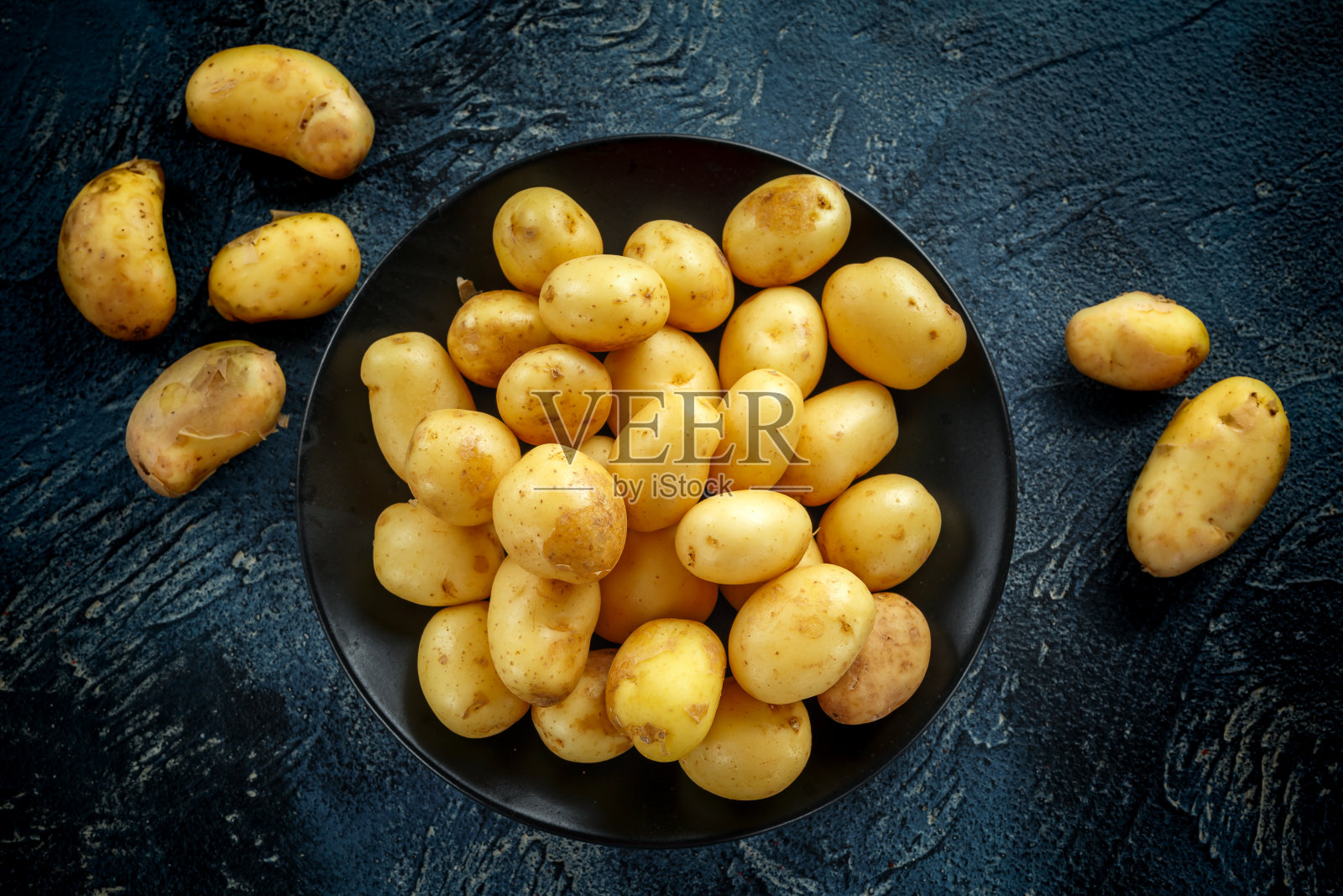 黑色盘子里的新生生土豆照片摄影图片