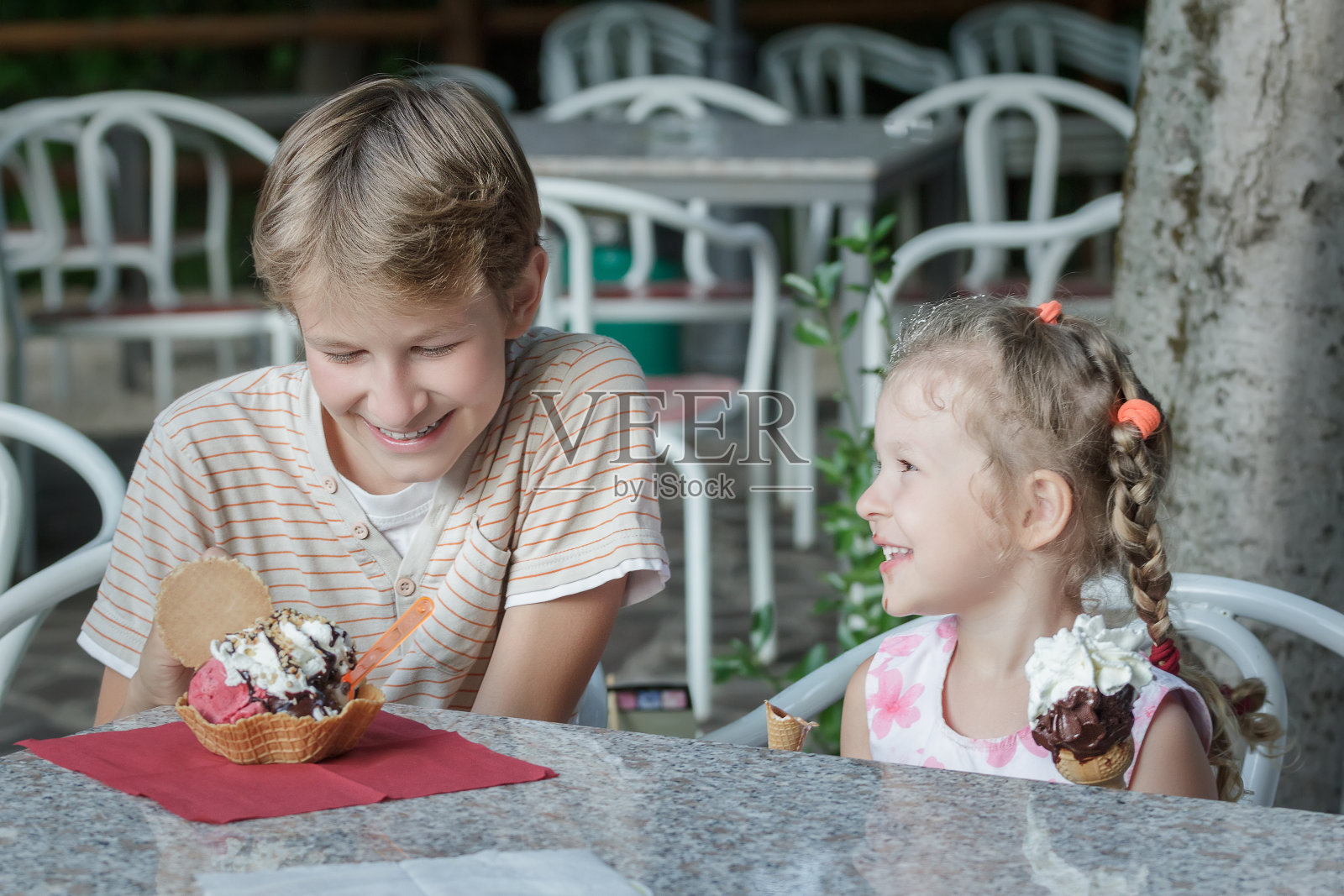 两个兄弟姐妹开心地吃着他们甜甜的意大利冰淇淋照片摄影图片