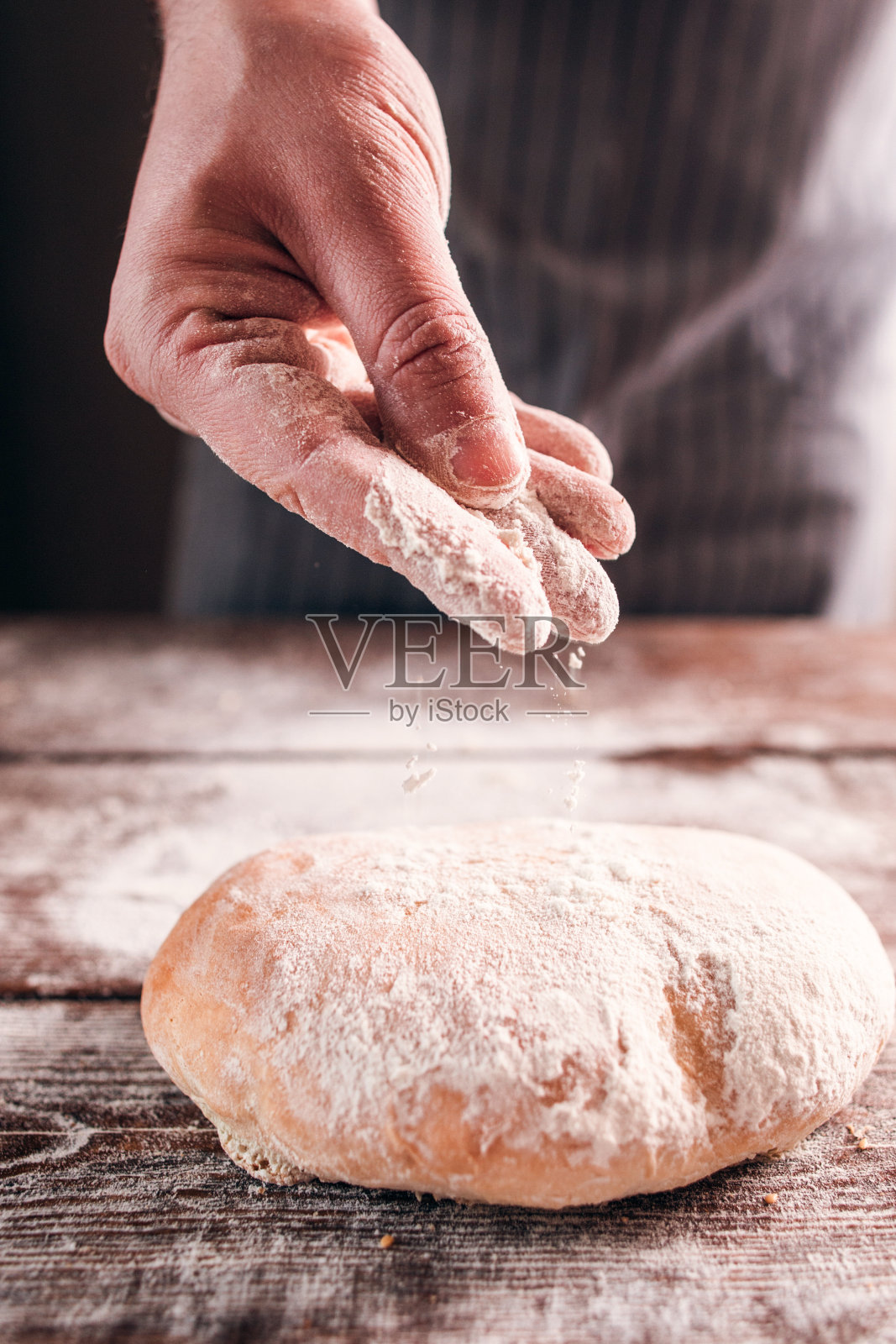 面包师用手把面粉洒在新鲜的小面包上照片摄影图片