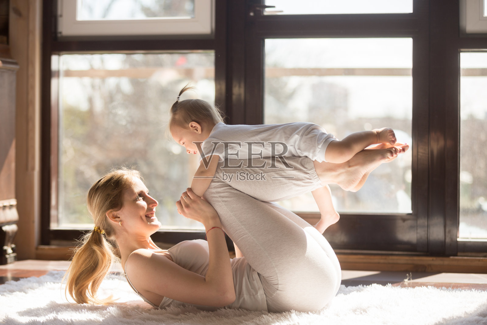 年轻微笑的瑜伽母亲和她的宝贝女儿锻炼照片摄影图片
