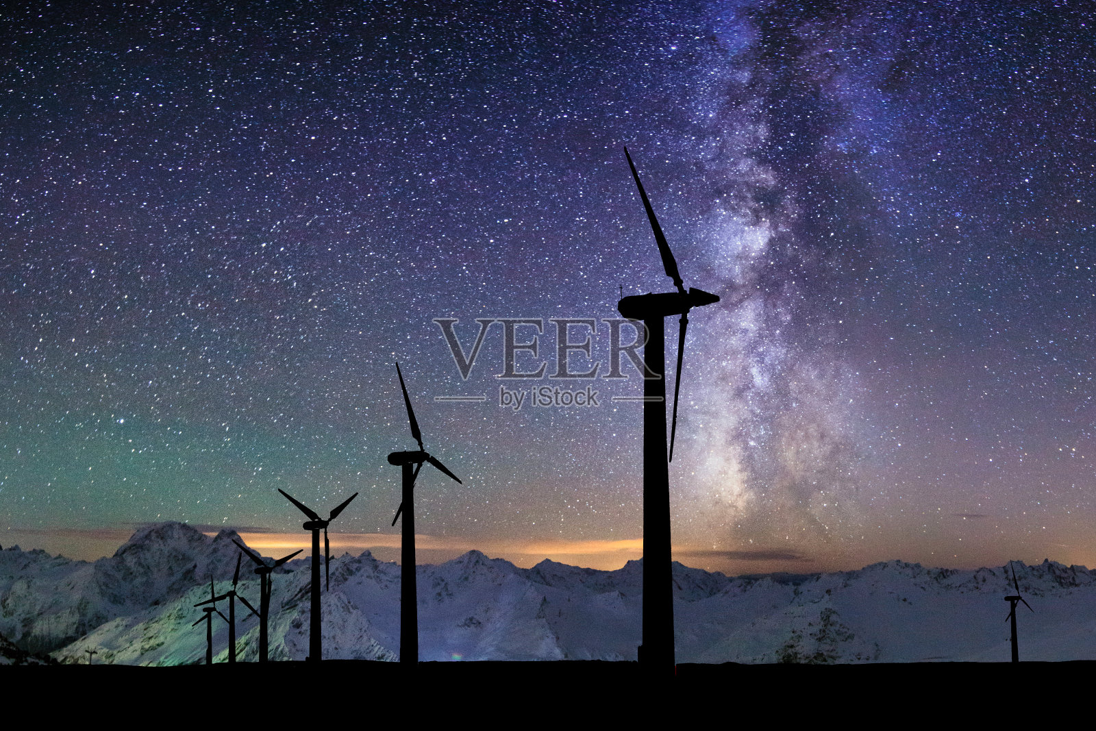 在群山和星空的背景下，风力涡轮机的剪影照片摄影图片