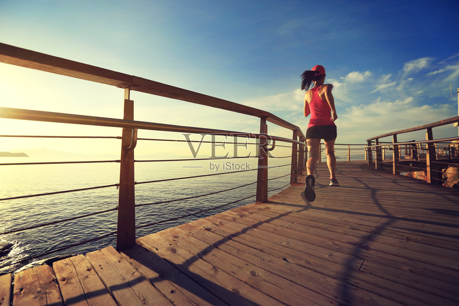 年轻的健身妇女跑步在日出的海滨木板路照片摄影图片