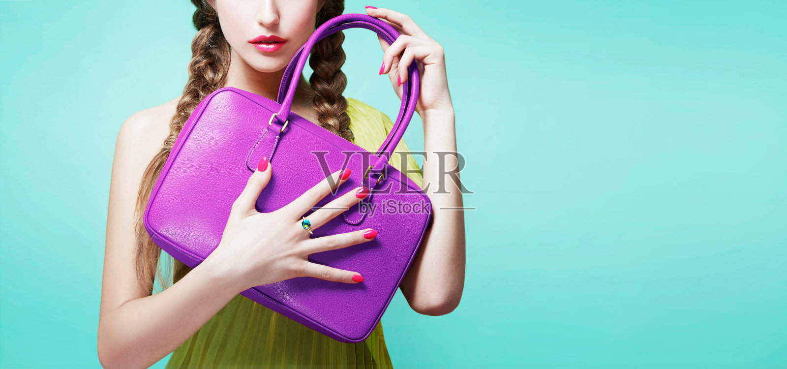 年轻的女孩拿着紫色的皮包钱包。孤立在明亮的水蓝色背景上。时尚物品的形象。照片摄影图片