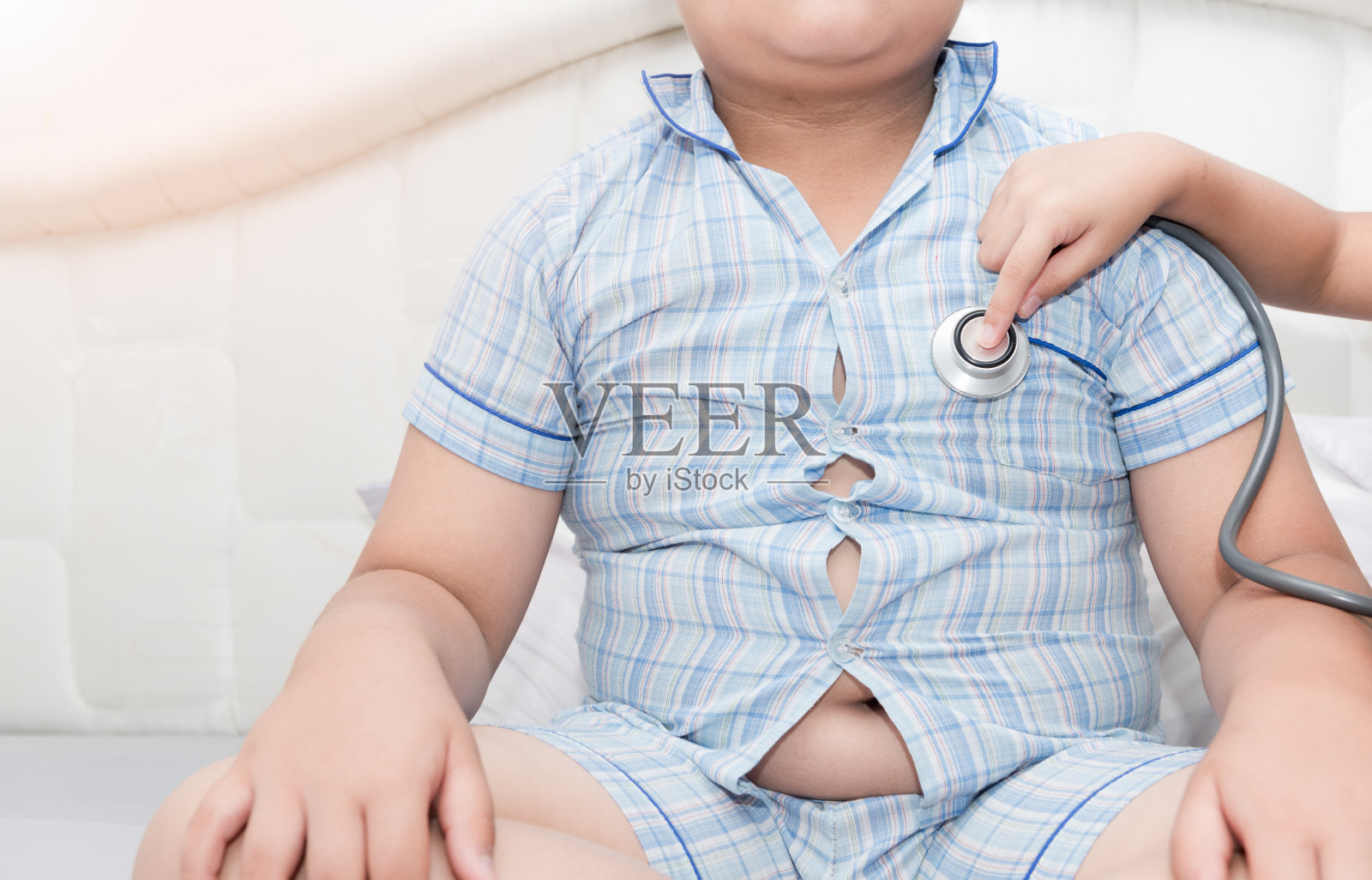 医生用听诊器给肥胖的亚洲男孩检查心脏照片摄影图片