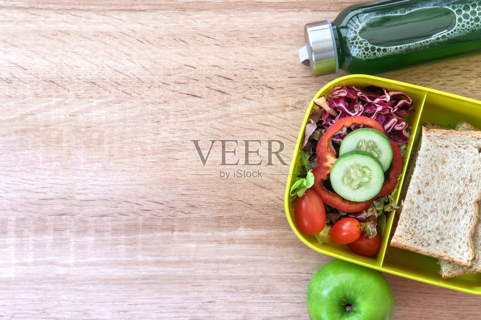 健康午餐盒与谷物面包和绿色蔬菜和果汁瓶在木制背景，健康饮食清洁饮食习惯的饮食概念，俯视图和头顶拍摄照片摄影图片