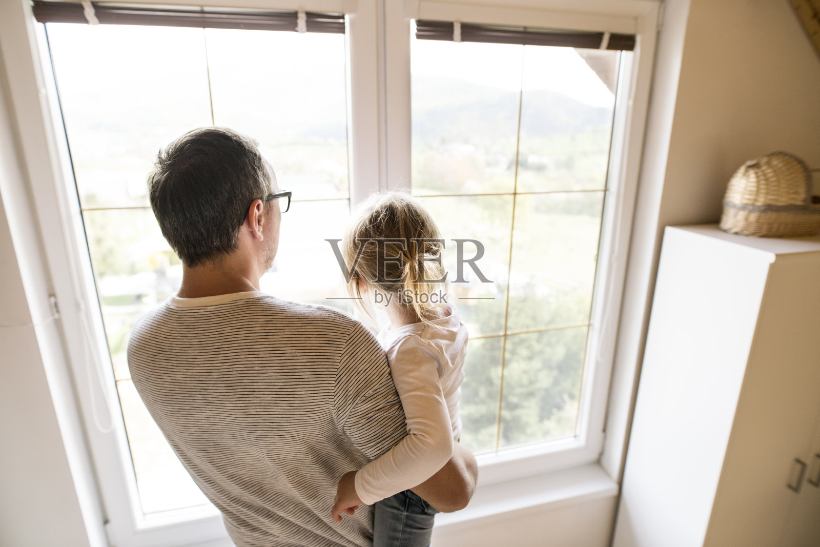 父亲和小女儿站在窗前。照片摄影图片