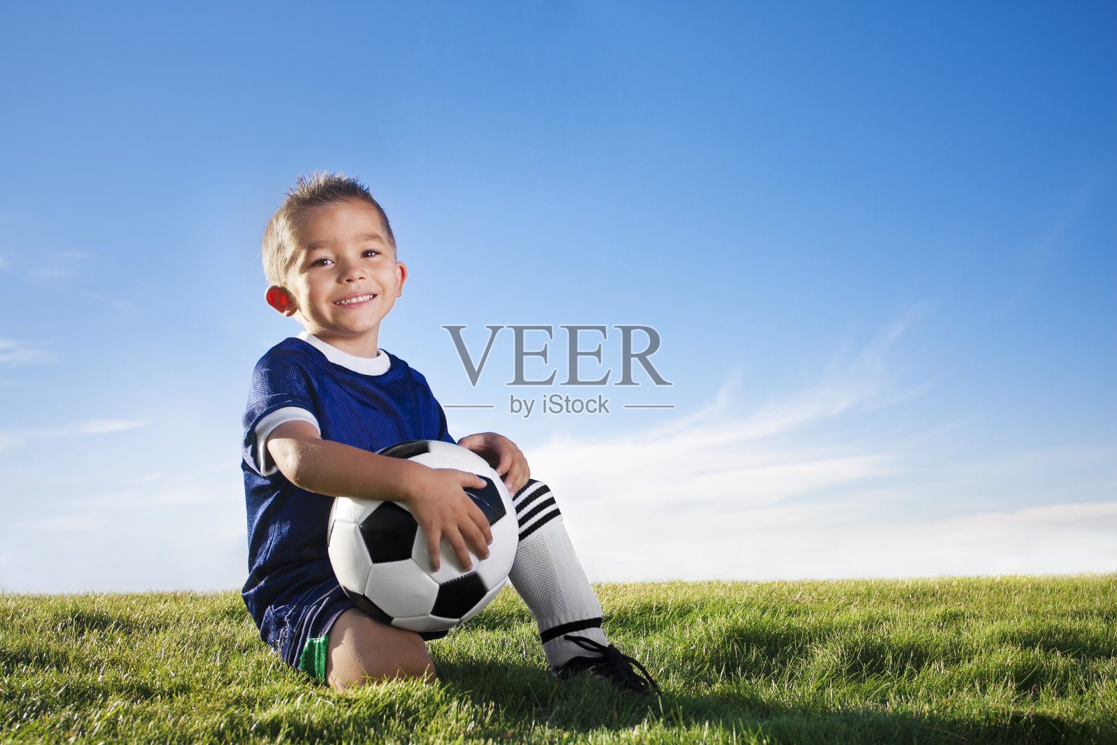 一个穿着足球制服的小男孩在球场上的肖像照片摄影图片
