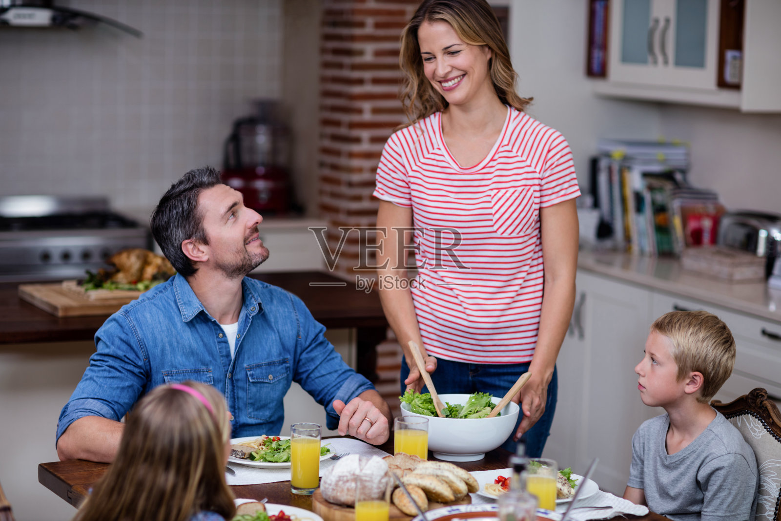 在厨房里为家人上菜的女人照片摄影图片