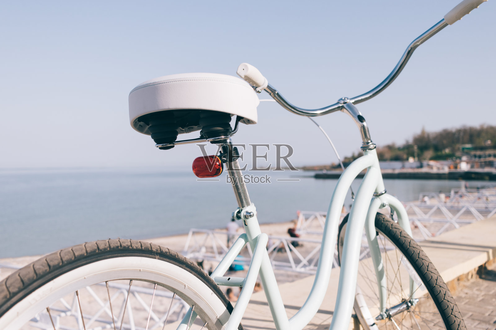蓝色复古自行车与白色座位在一个阳光明媚的夏天傍晚的背景下的大海照片摄影图片