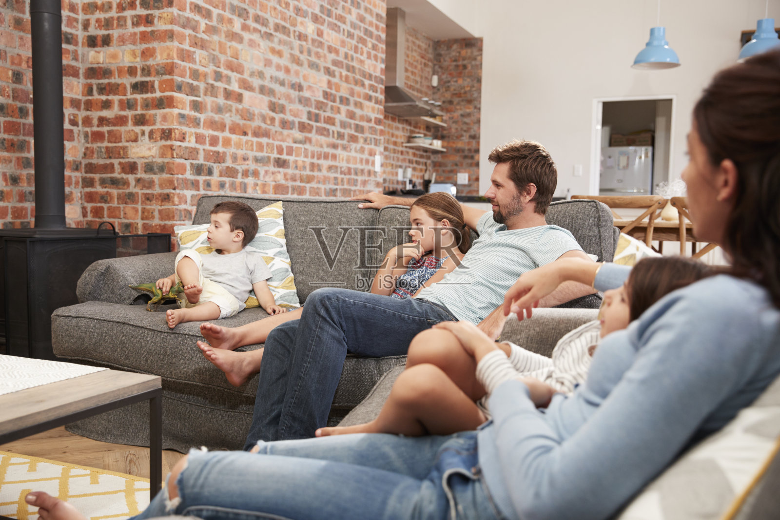 一家人坐在开放式休息室的沙发上看电视照片摄影图片