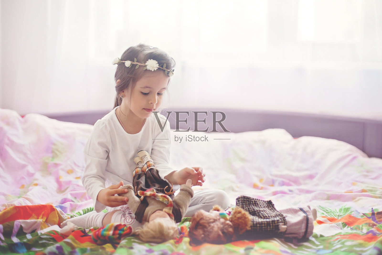 可爱的小女孩，在家里的床上玩洋娃娃照片摄影图片