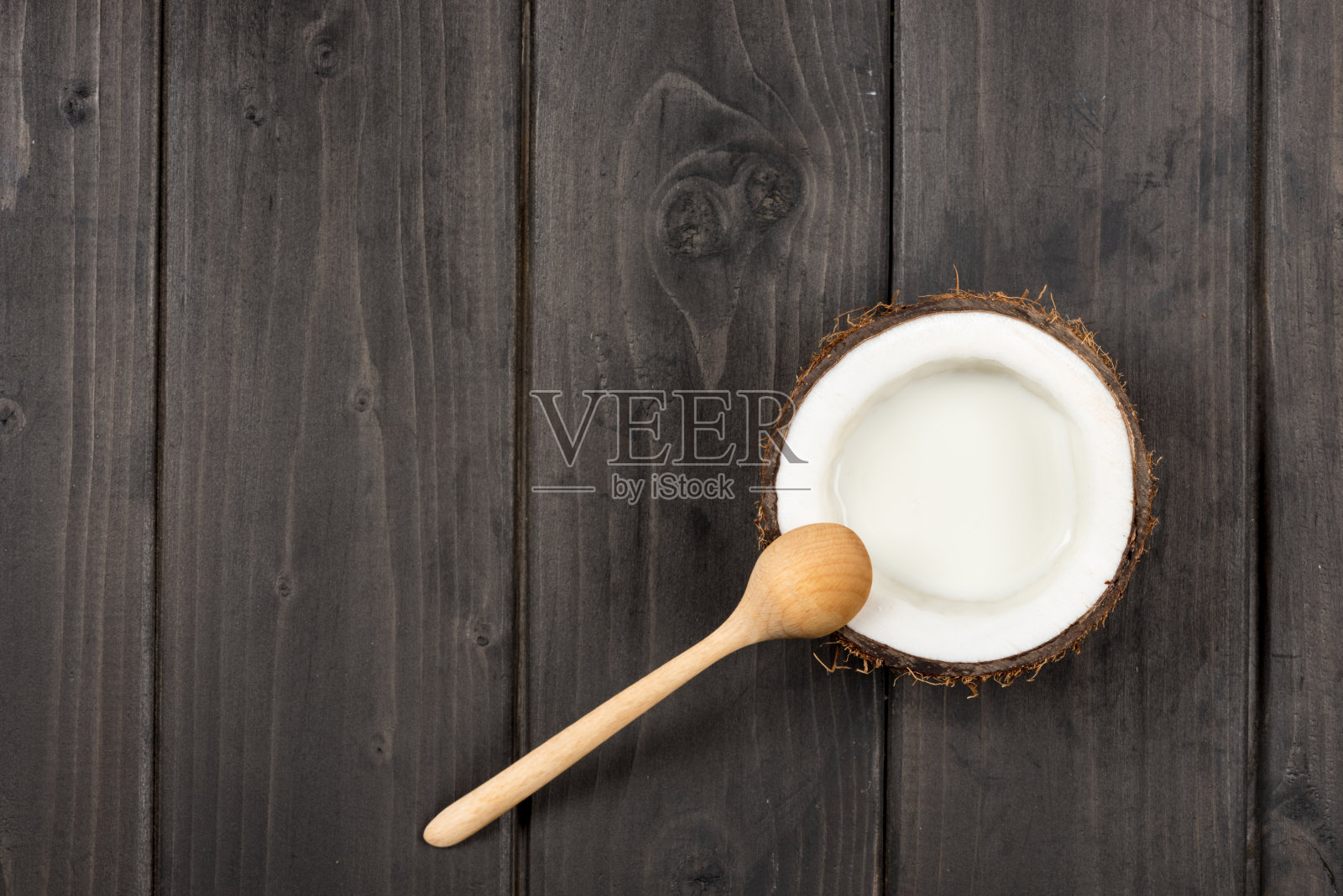 俯视图的成熟椰子一半用牛奶和木勺，椰奶照片摄影图片