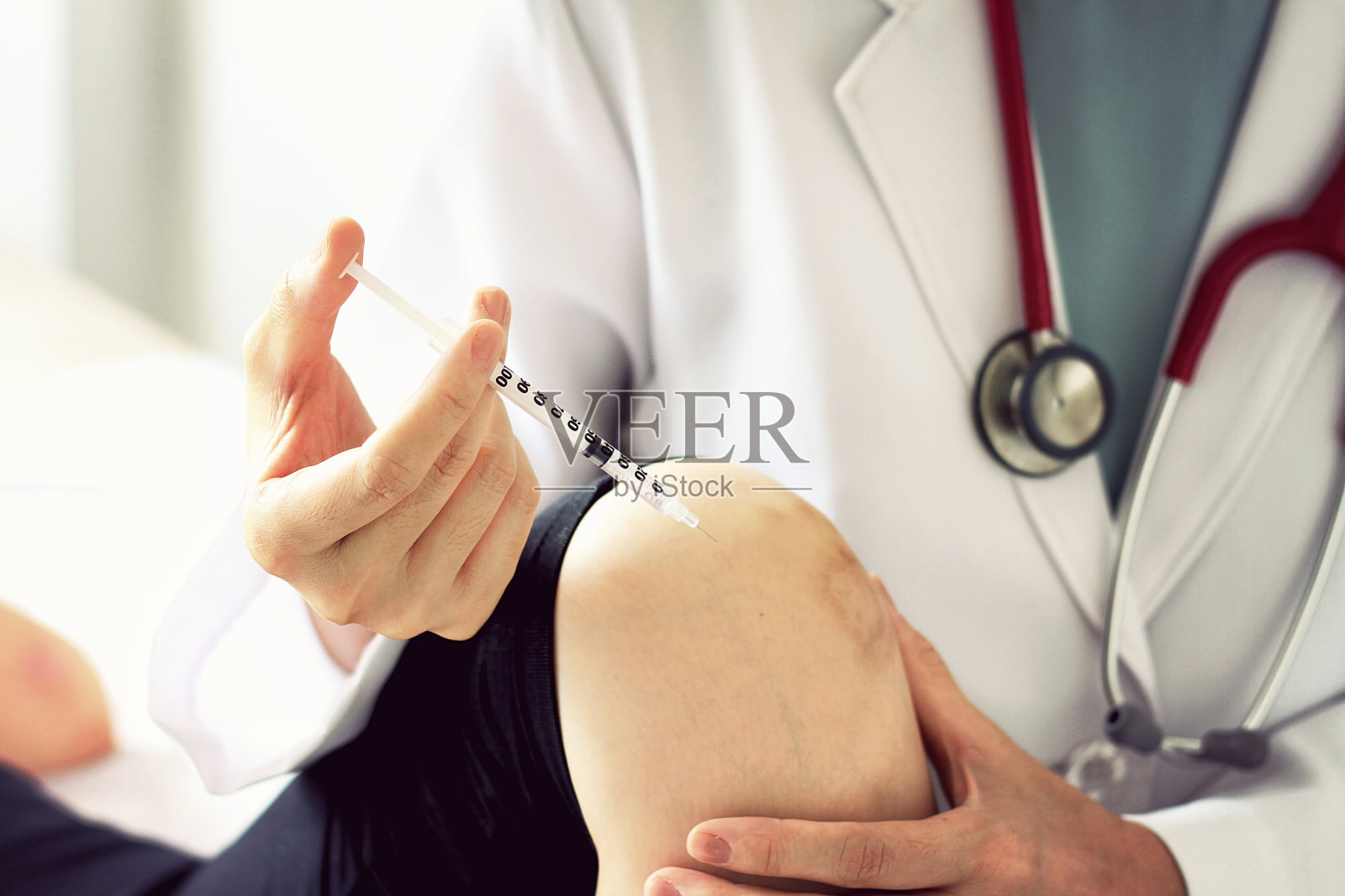 医生给年轻女病人打针，检查膝关节疼痛，运动损伤。照片摄影图片