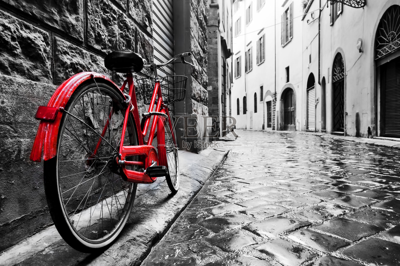 复古的红色自行车在老城的鹅卵石街道上。颜色在黑色和白色照片摄影图片