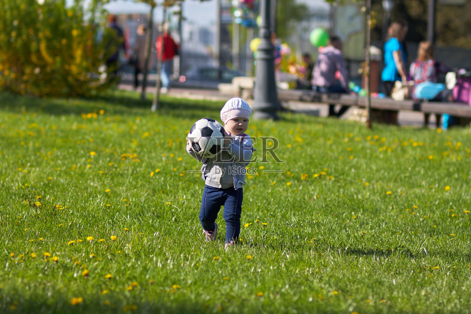 小女孩，金发的婴儿在户外。活跃的足球迷在奔跑照片摄影图片